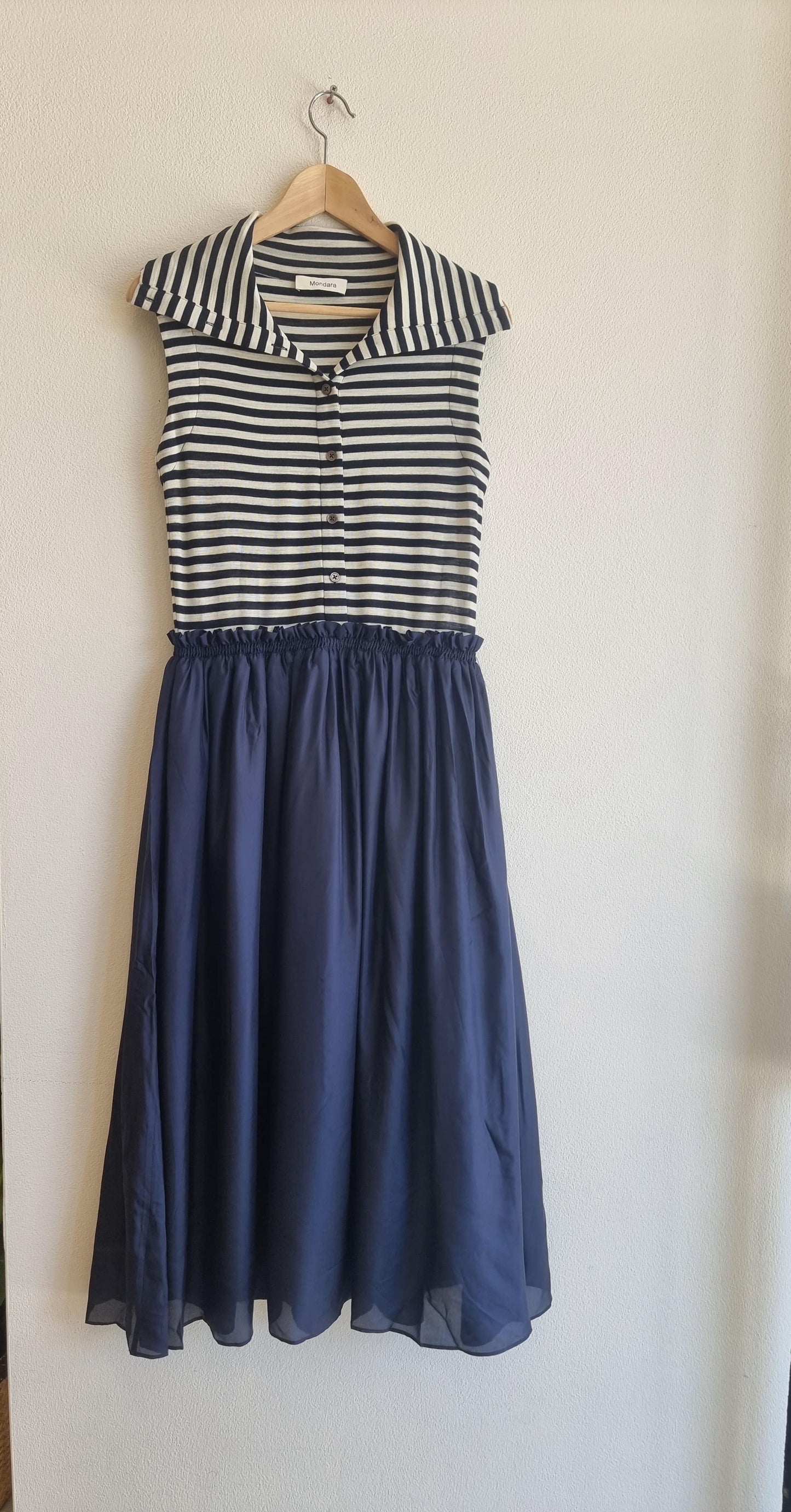 Navy silk skirt dress with elastic waist and cotton lining, featuring a striped sleeveless top, displayed on a hanger against a white wall.