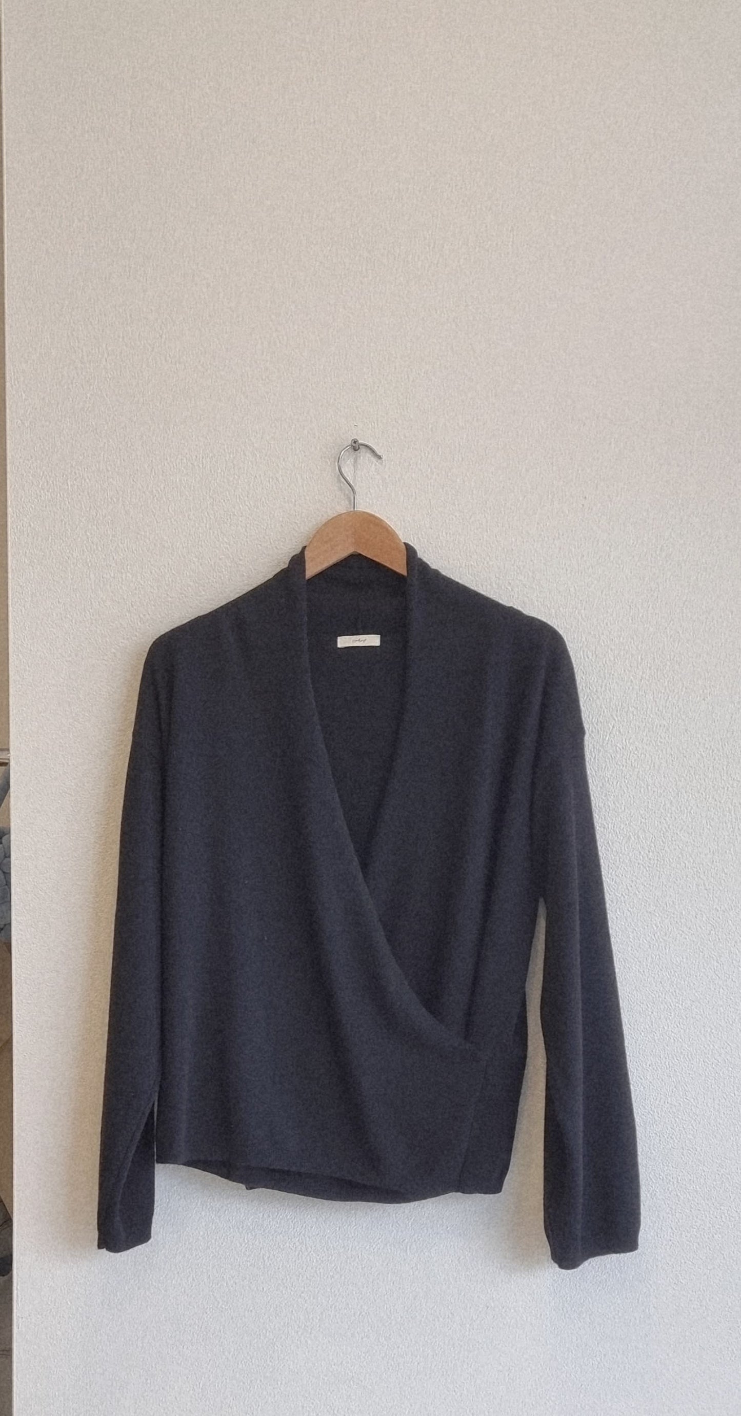 Black wrap knit top hanging on hanger, product only