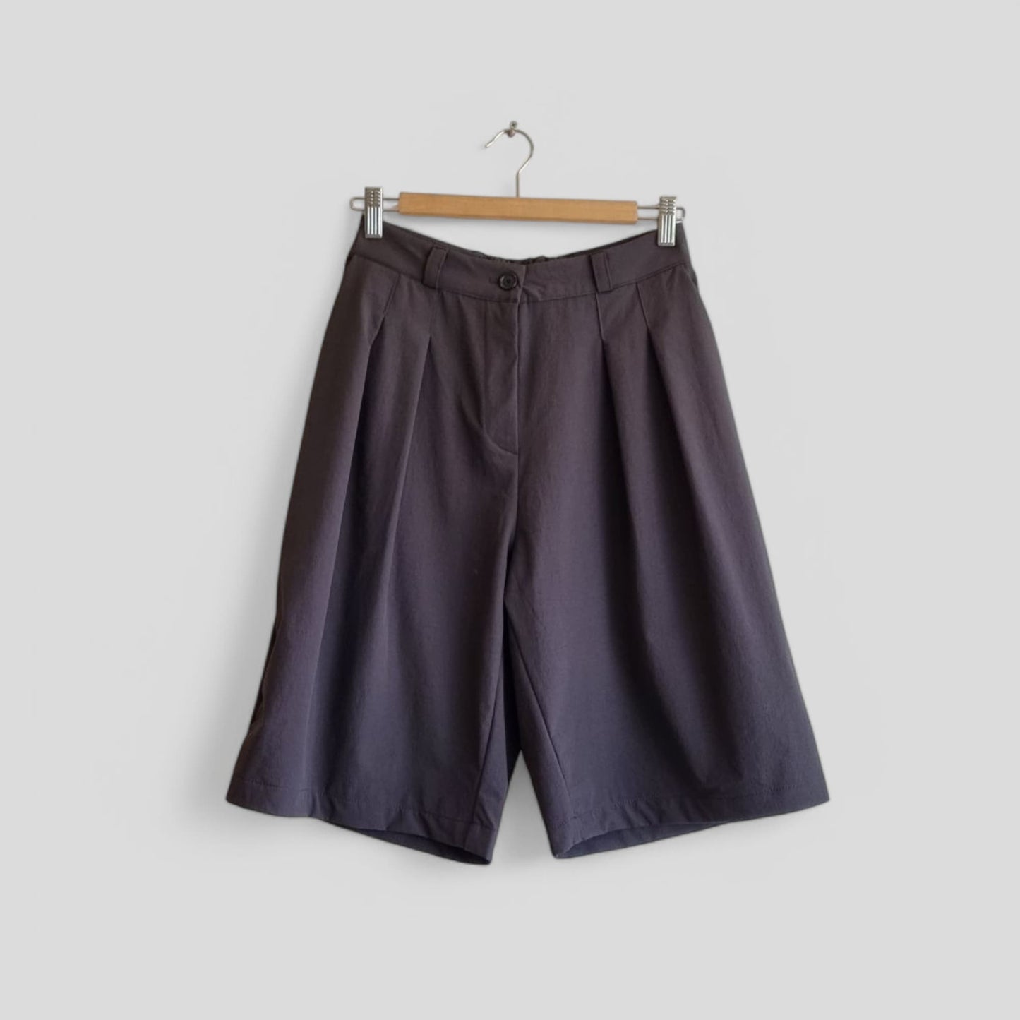 Dark wide-leg pants hanging on a wooden hanger – front view