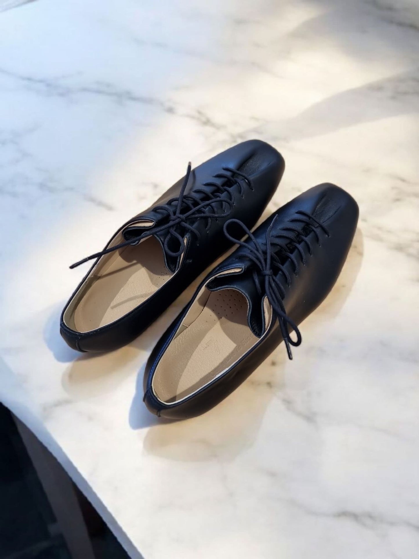 Black leather lace-up shoes with natural lighting – front view