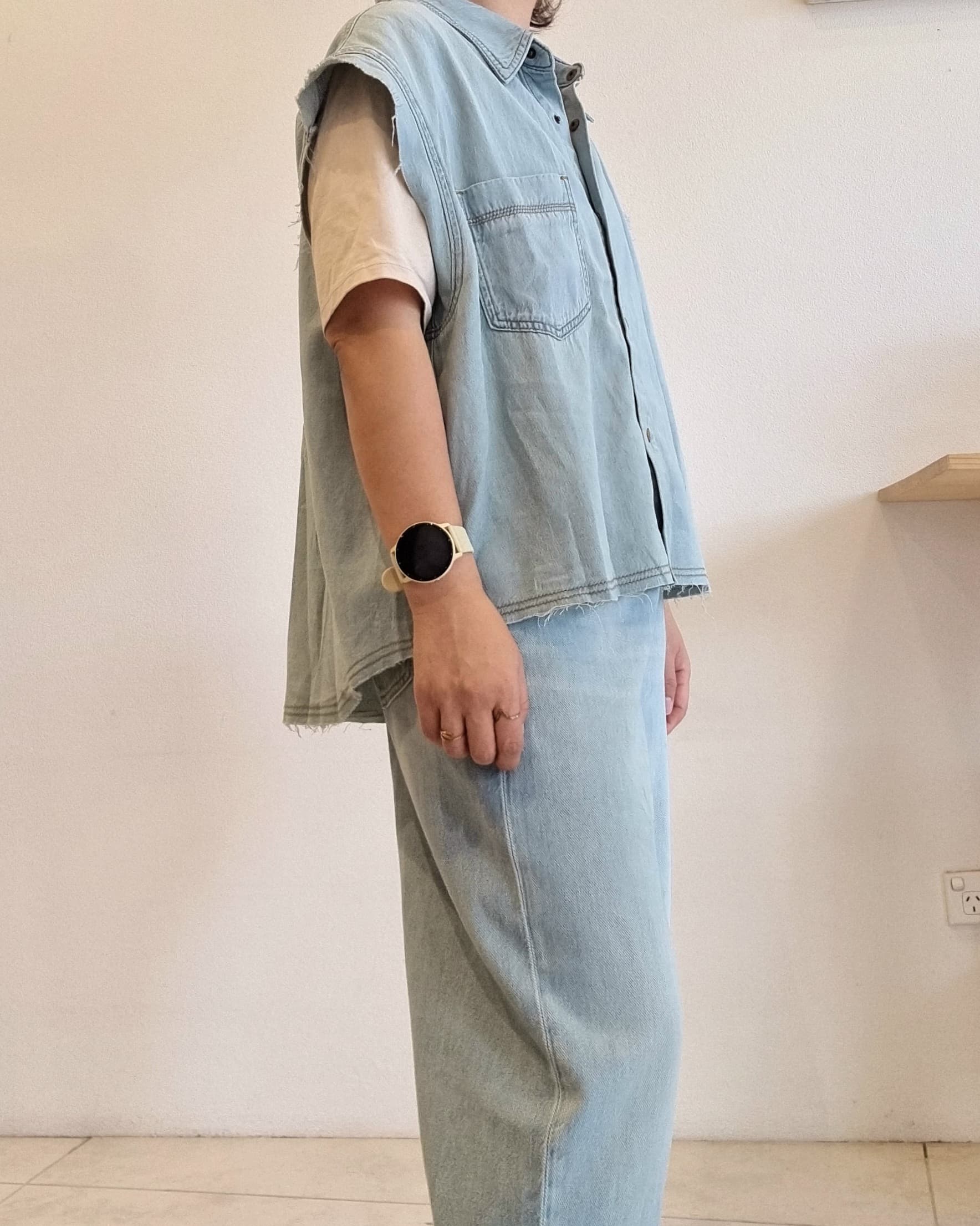 Light denim cotton vest, angled side view highlighting snap buttons.