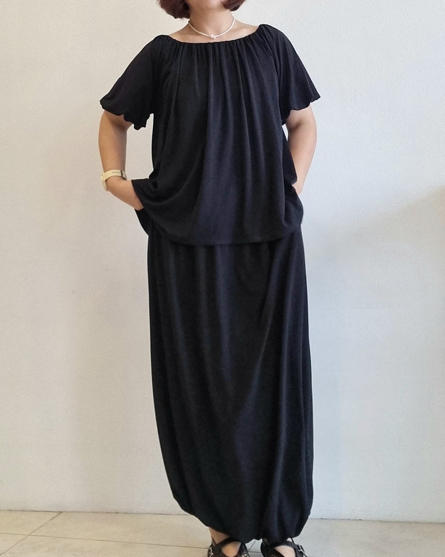 “Front view of a woman wearing the Seren Black Set with a relaxed top and balloon-style long skirt.”