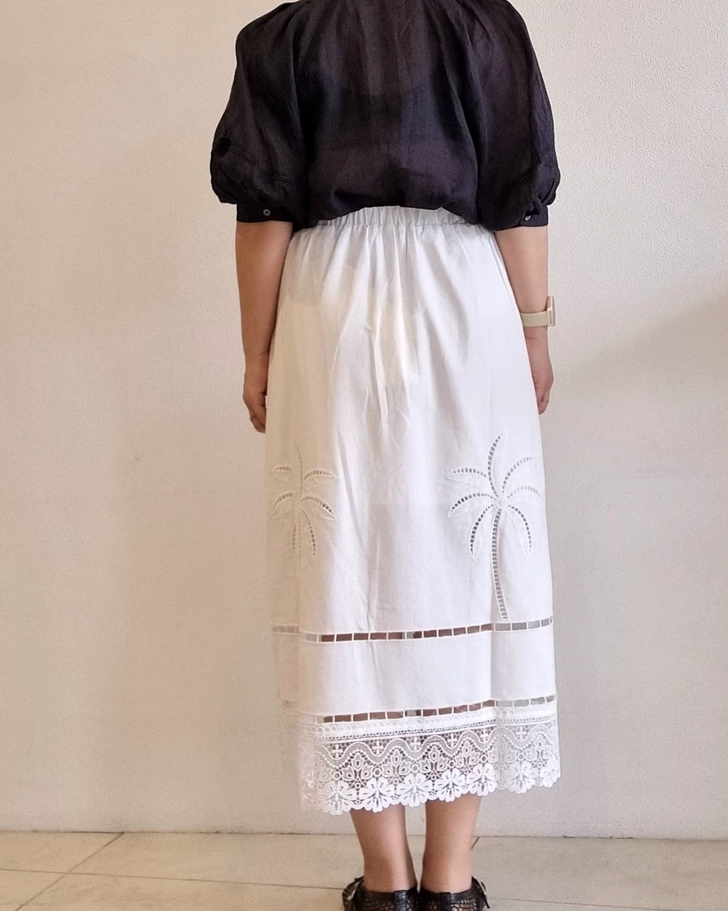 “Back view of the Palmera Lace Skirt showing the elastic waistband, palm embroidery, and scalloped lace hem.”