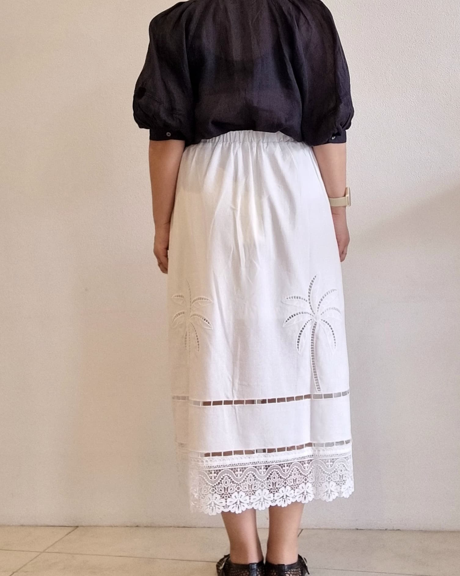 “Back view of the Palmera Lace Skirt showing the elastic waistband, palm embroidery, and scalloped lace hem.”