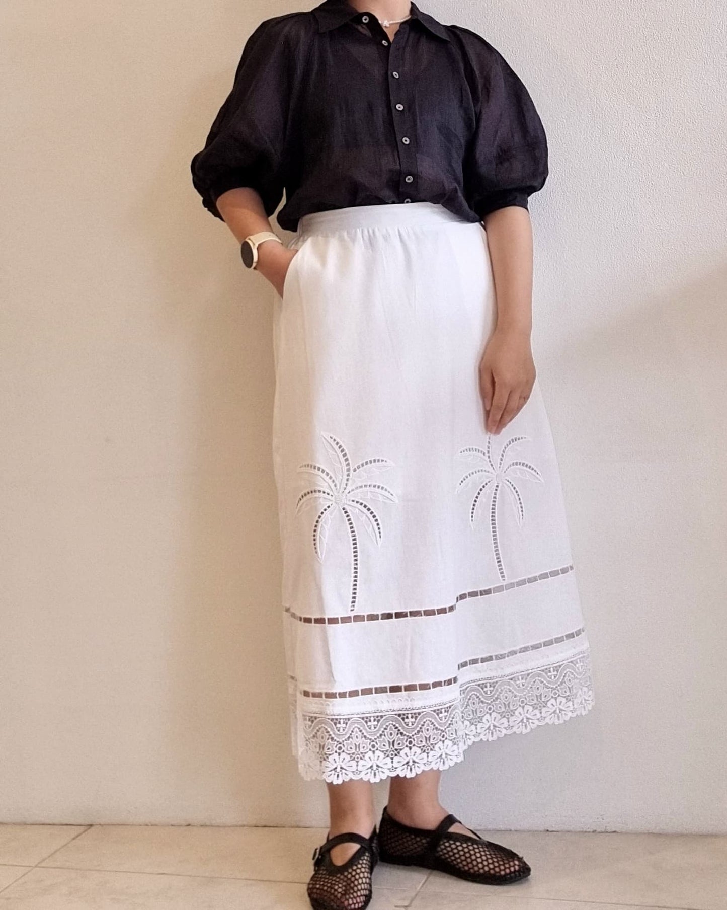 Model wearing the Palmera Lace Skirt with palm embroidery and lace hem.
