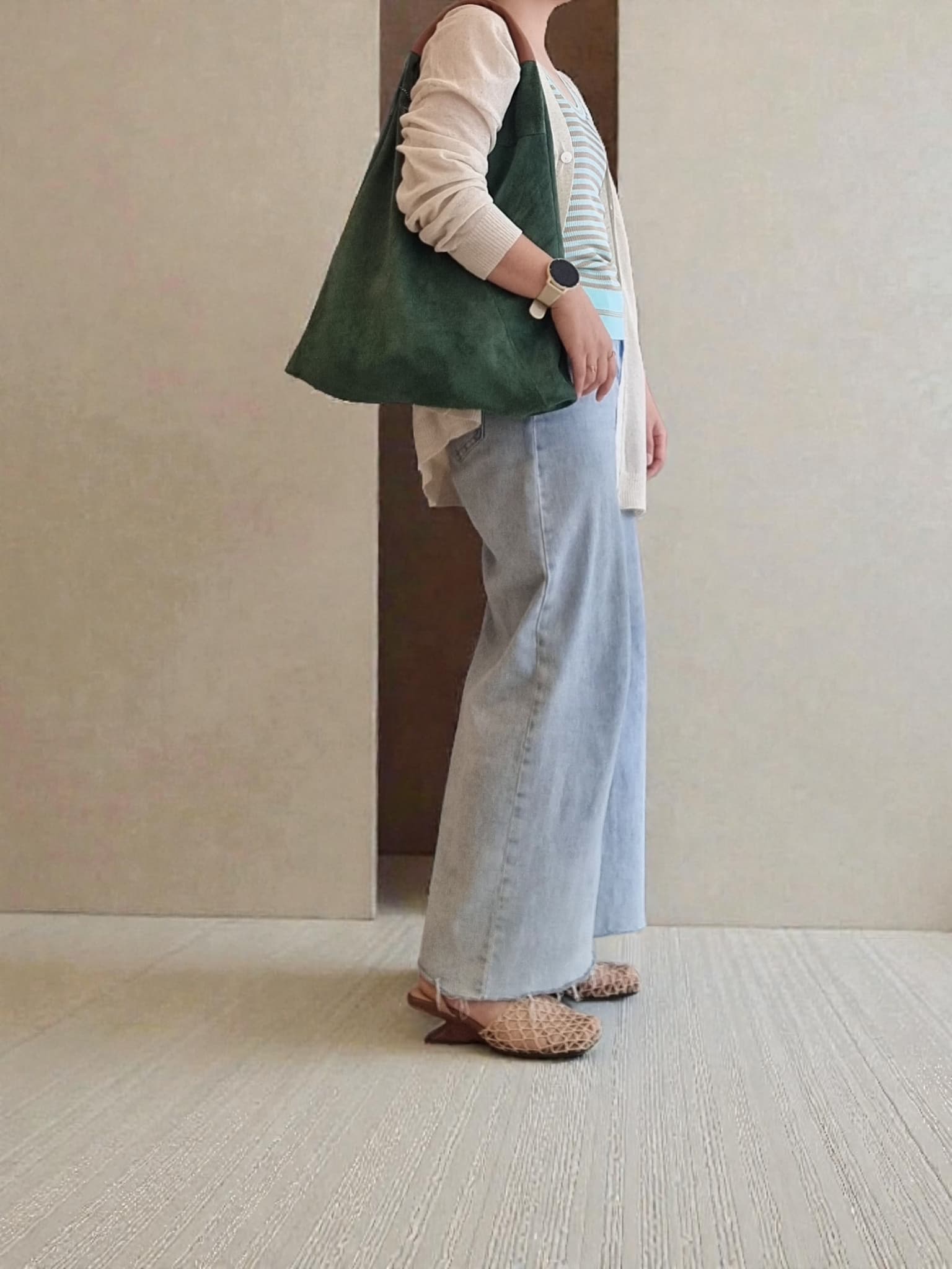 “Model carrying a green Italian suede shoulder bag with a soft slouchy design, styled indoors against a minimal beige backdrop.”