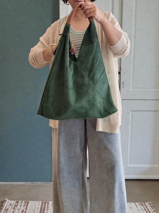 “Model holding a green Italian suede shoulder bag with a soft slouchy silhouette, featuring zipper closure and matching mini pouch – Nova Lux”