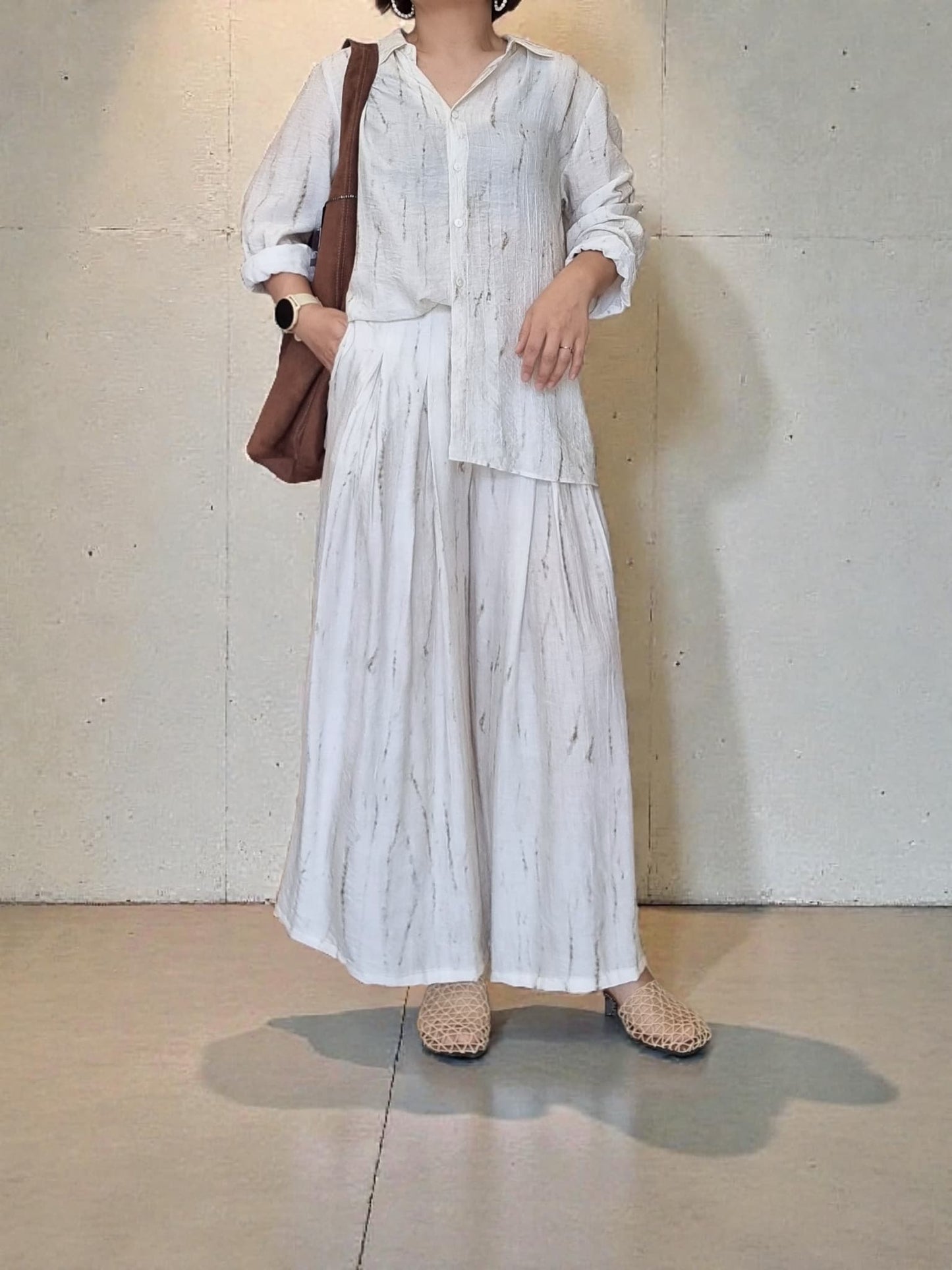 “Oceanus wrinkle-free lightweight shirt and wide-leg pants set worn by model, natural marble pattern outfit styled with a brown shoulder bag against a neutral wall background – Nova Lux”