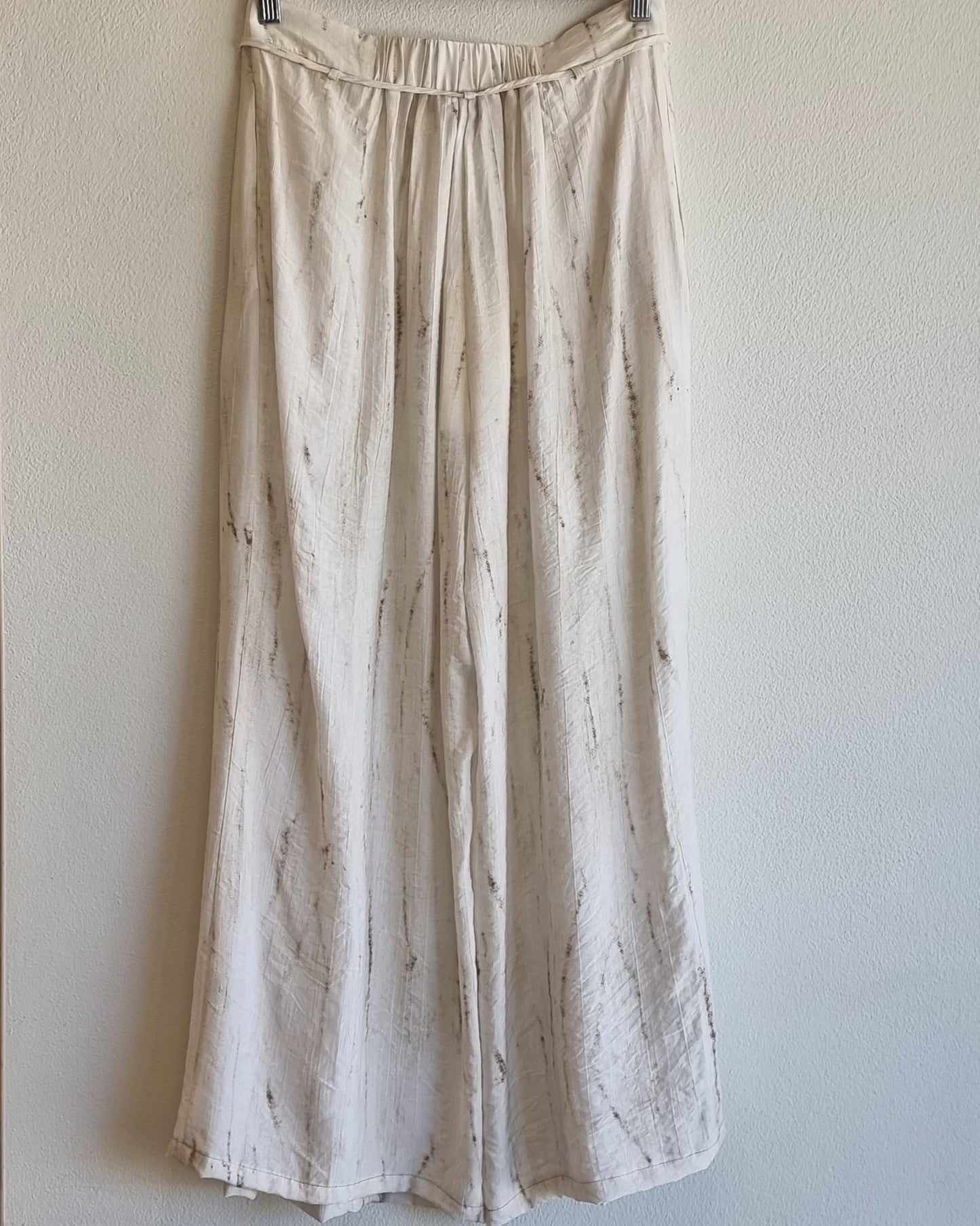 “Front product view of the Oceanus wrinkle-free lightweight wide-leg pants hanging against a neutral wall, showing natural marble-pattern fabric – Nova Lux”