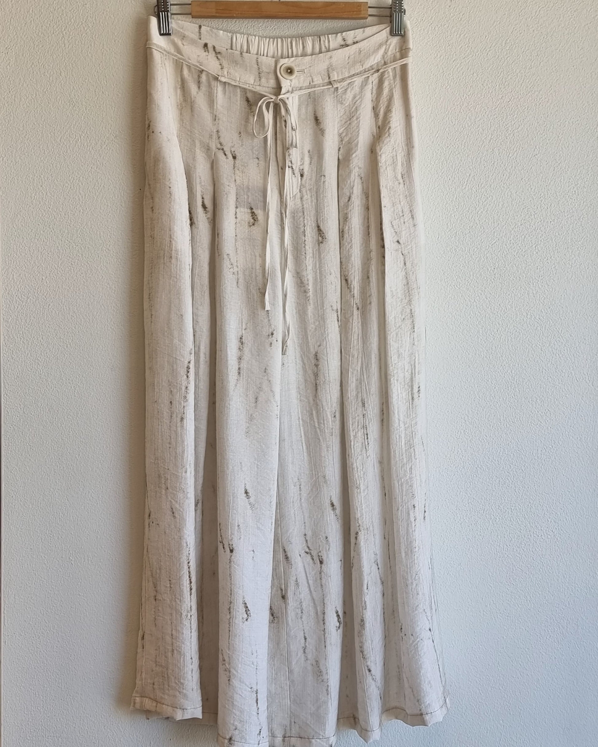 “Front view of the Oceanus wrinkle-free lightweight wide-leg pants hanging against a neutral wall, showing marble-pattern fabric and drawstring waistband detail – Nova Lux”