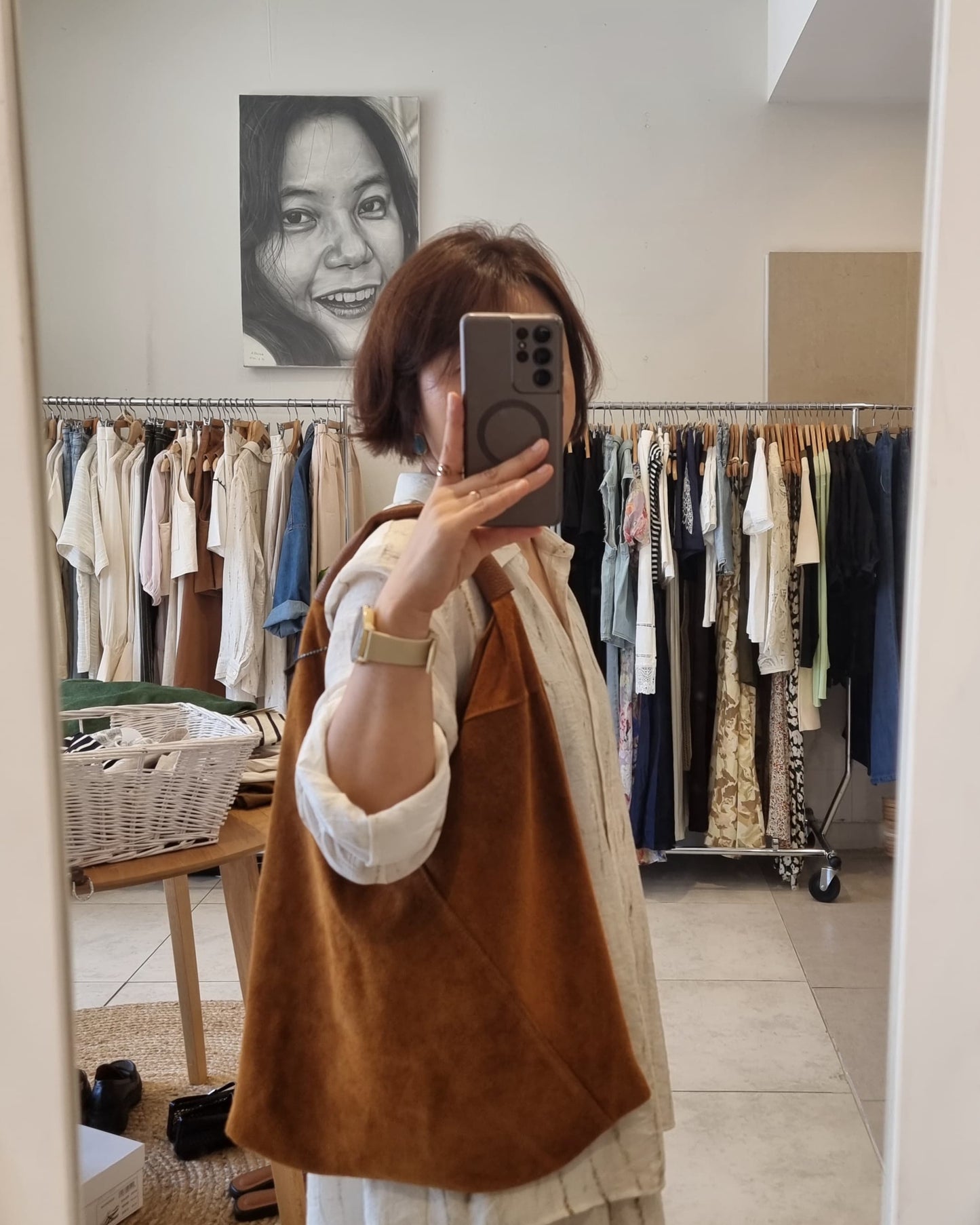 “Mirror selfie showing a brown Italian suede shoulder bag worn in a boutique clothing store.”