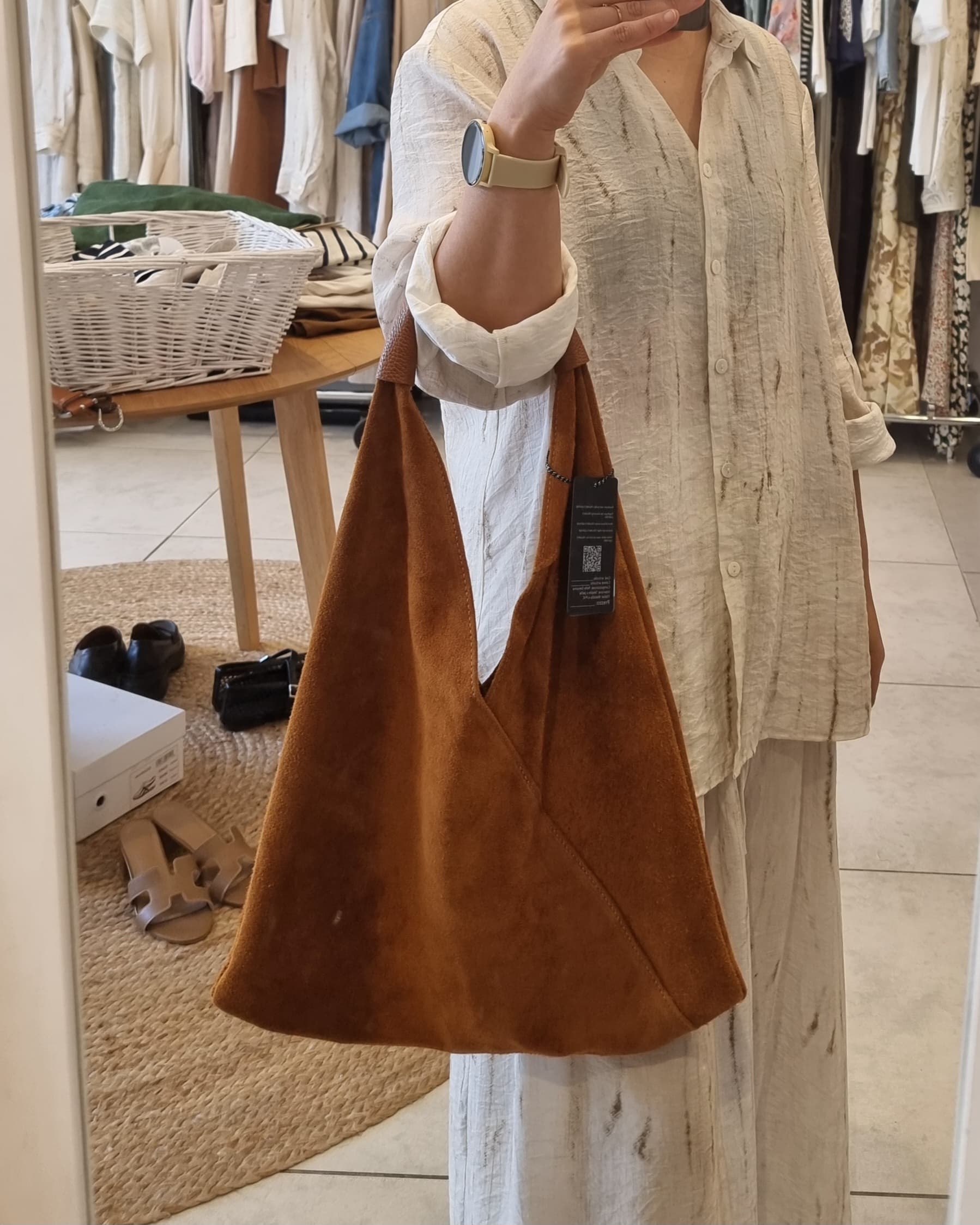 “Brown Italian suede shoulder bag with leather handle, shown in a boutique fitting room while held for size reference — includes visible brand tag.”