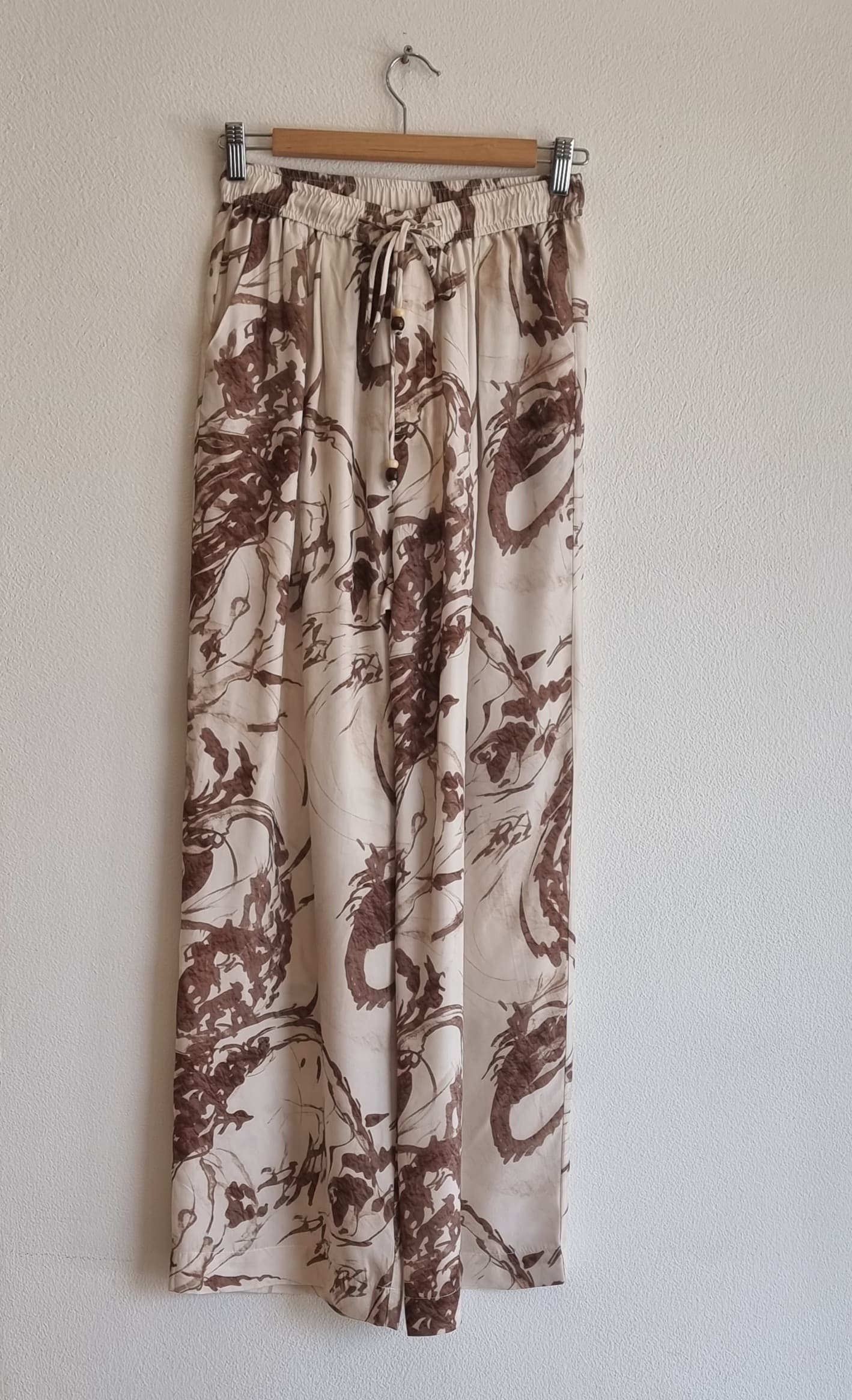 Printed wide-leg pants with elastic waistband displayed on a hanger against a neutral background.