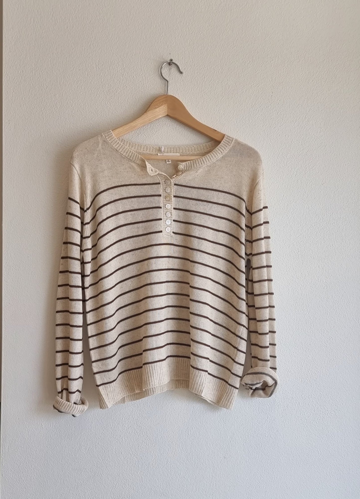 “Beige cotton summer knit top with brown stripes hanging on a wooden hanger.”