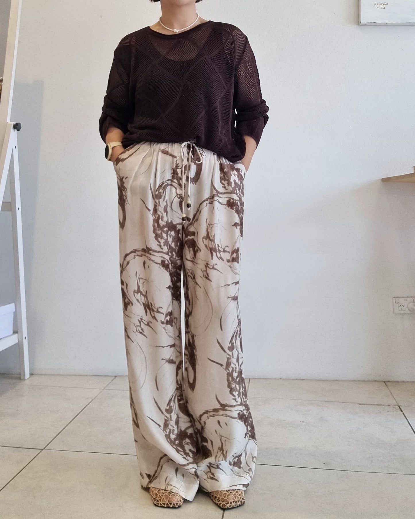 Brown semi-sheer Tencel mesh knit top paired with beige abstract print pants.