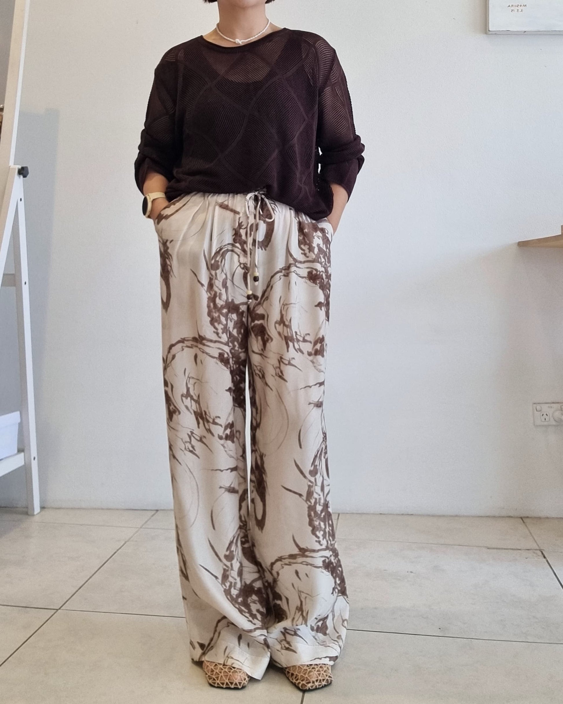 Brown semi-sheer Tencel mesh knit top paired with beige abstract print pants.