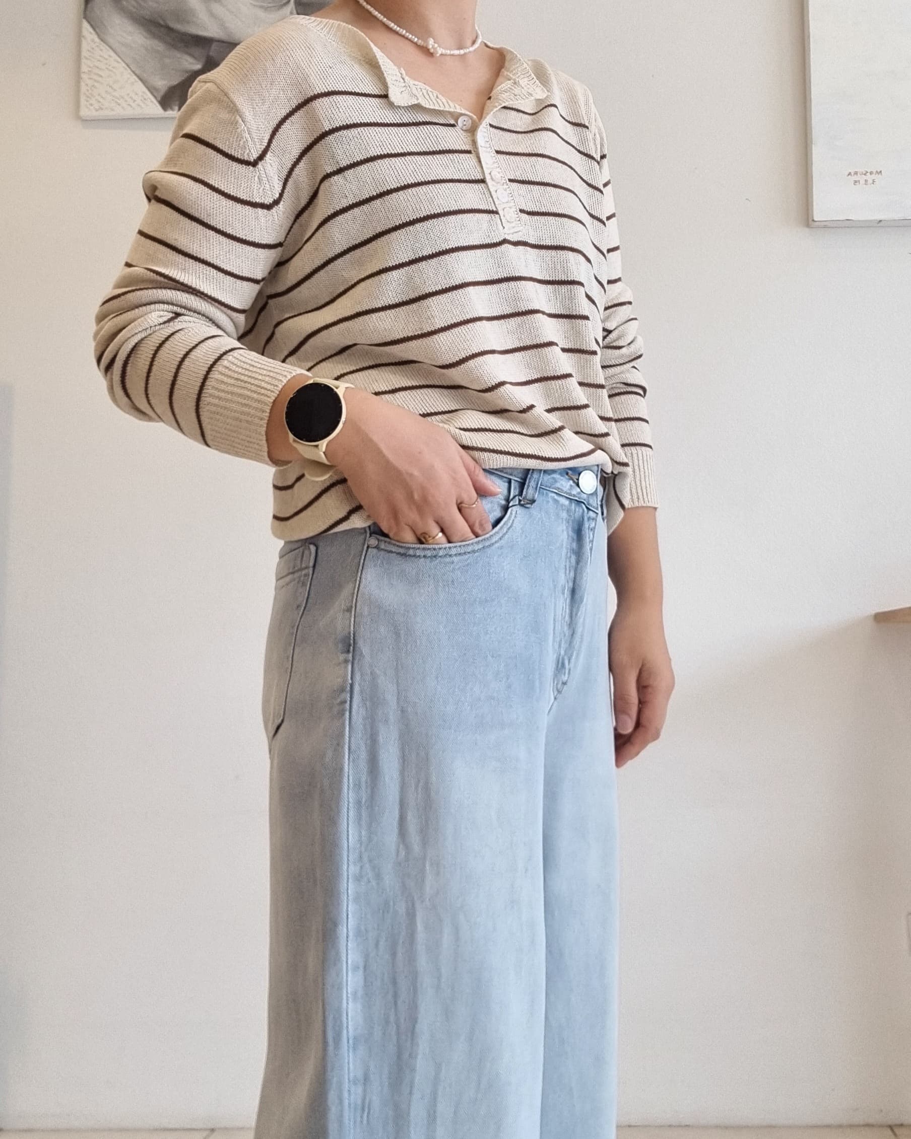 “Model wearing a beige cotton summer knit top with brown stripes, styled with light blue wide-leg denim jeans.”