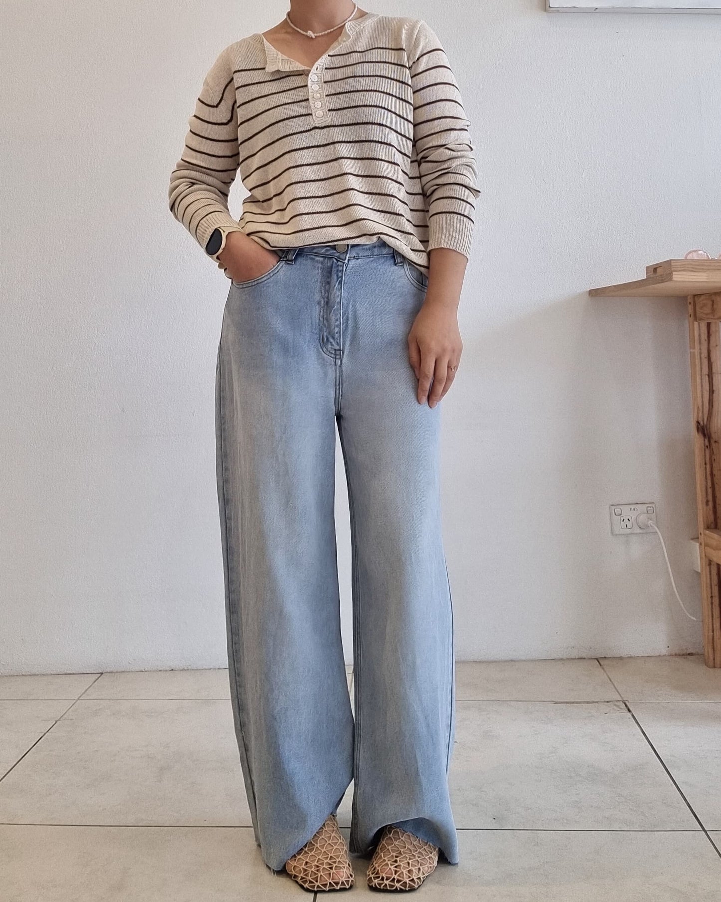 Model wearing a beige and brown striped cotton summer knit top styled with wide-leg denim.