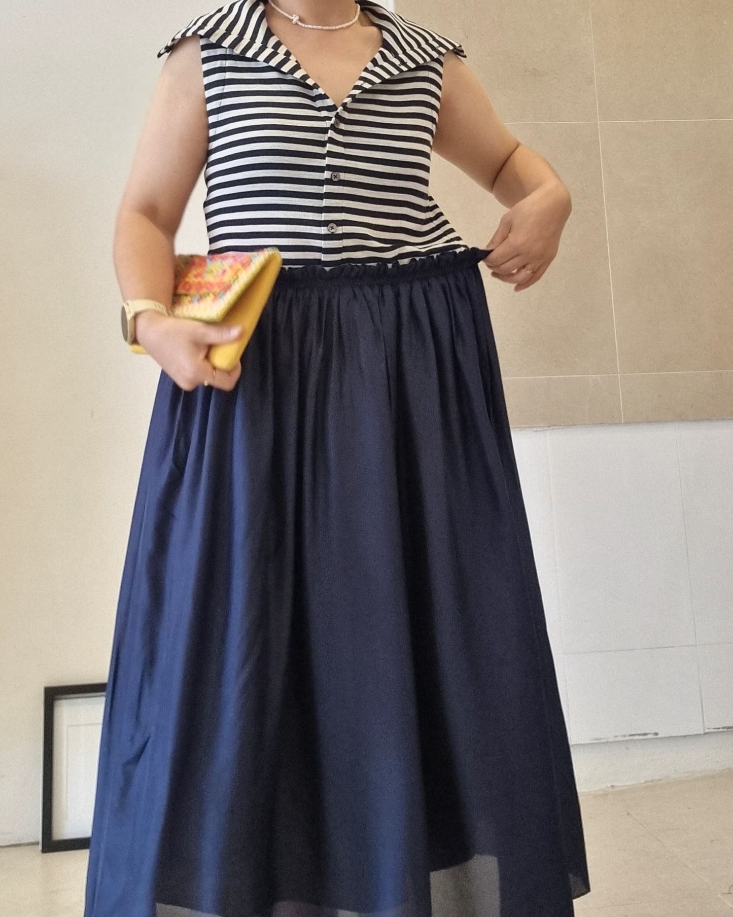 “Navy silk maxi skirt with elastic waistband styled with striped sleeveless top, front detail view.”