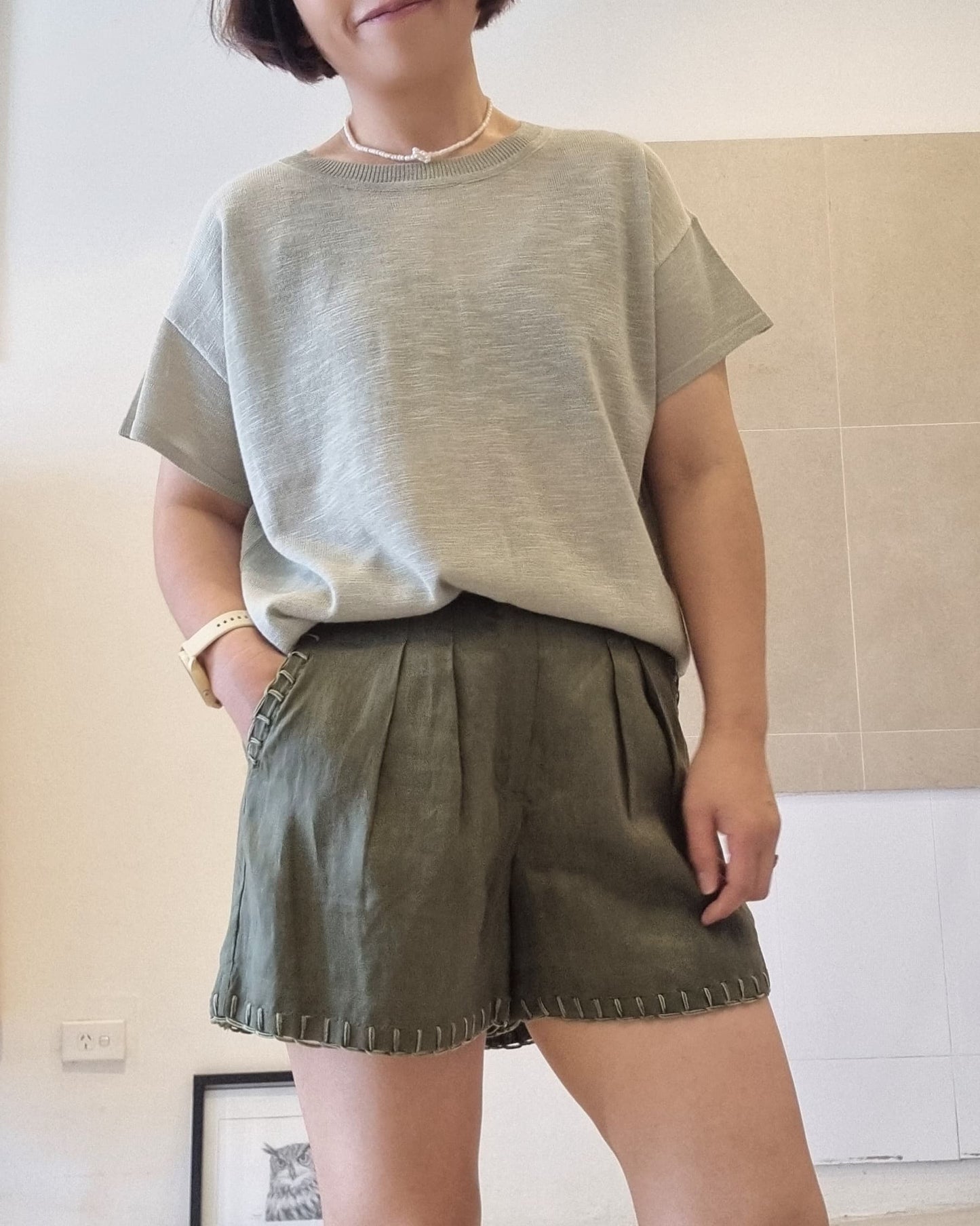 Soft green viscose knit top worn by model, relaxed fit, styled with olive green shorts