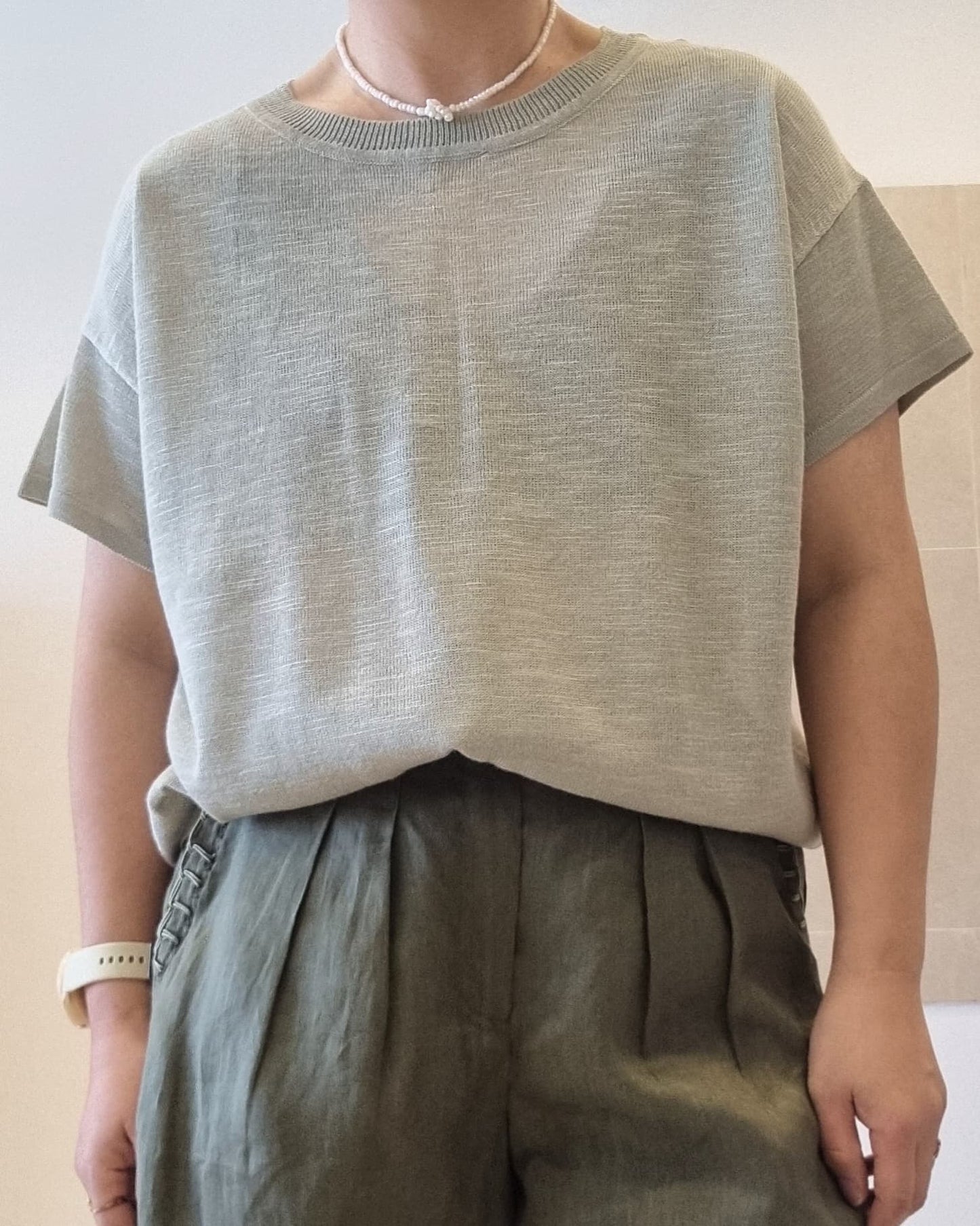 Soft green viscose knit top worn by model, relaxed fit, styled with dark green trousers
