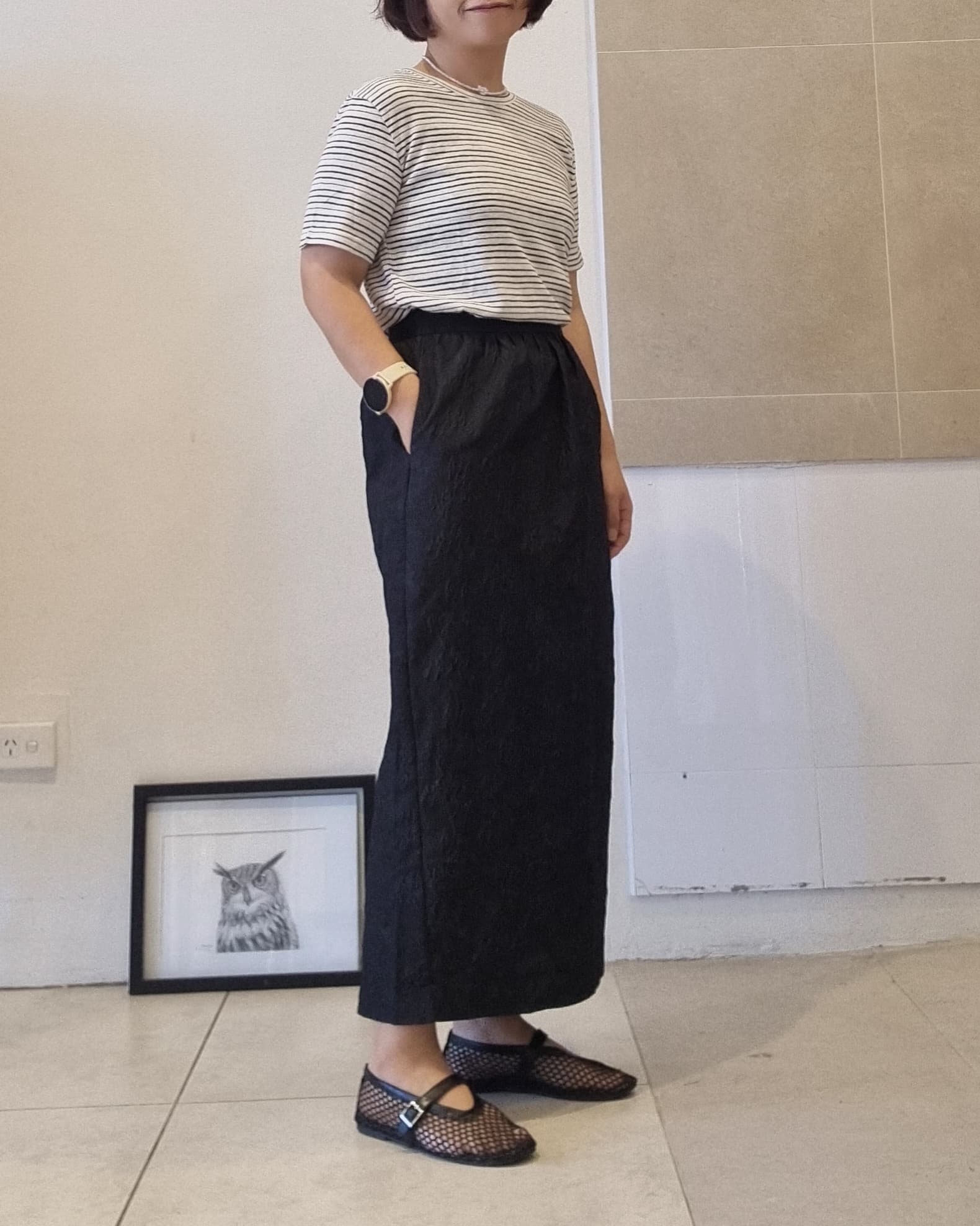 Side view of black stripe cotton linen t-shirt styled with long black skirt, relaxed fit