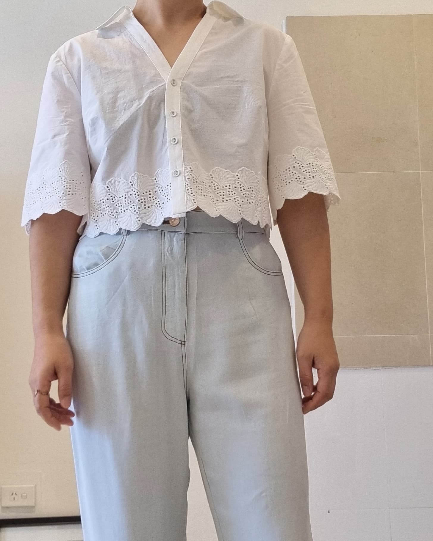 White cotton eyelet lace blouse with button front and scalloped hem, front detail view