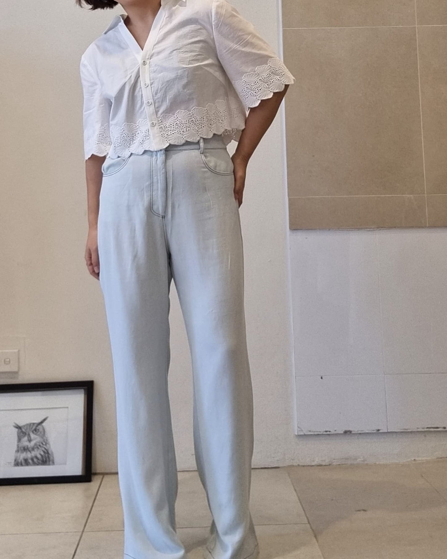 White cotton eyelet lace blouse styled with light blue high-waist pants, front button detail, Nova Lux