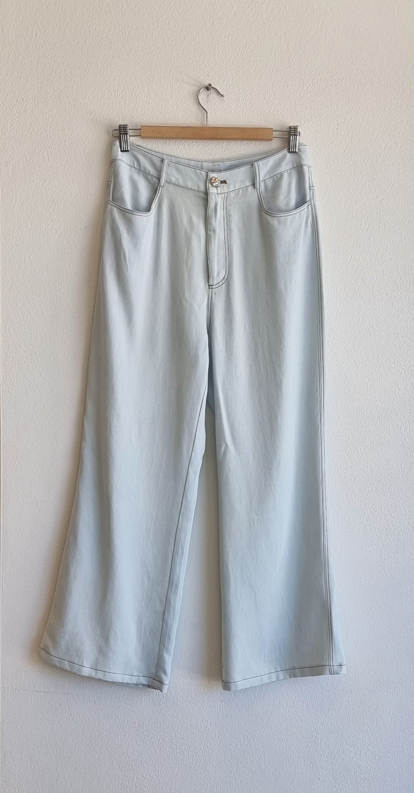 Light blue Tencel wide-leg pants on hanger, high-waist fit with soft fluid drape