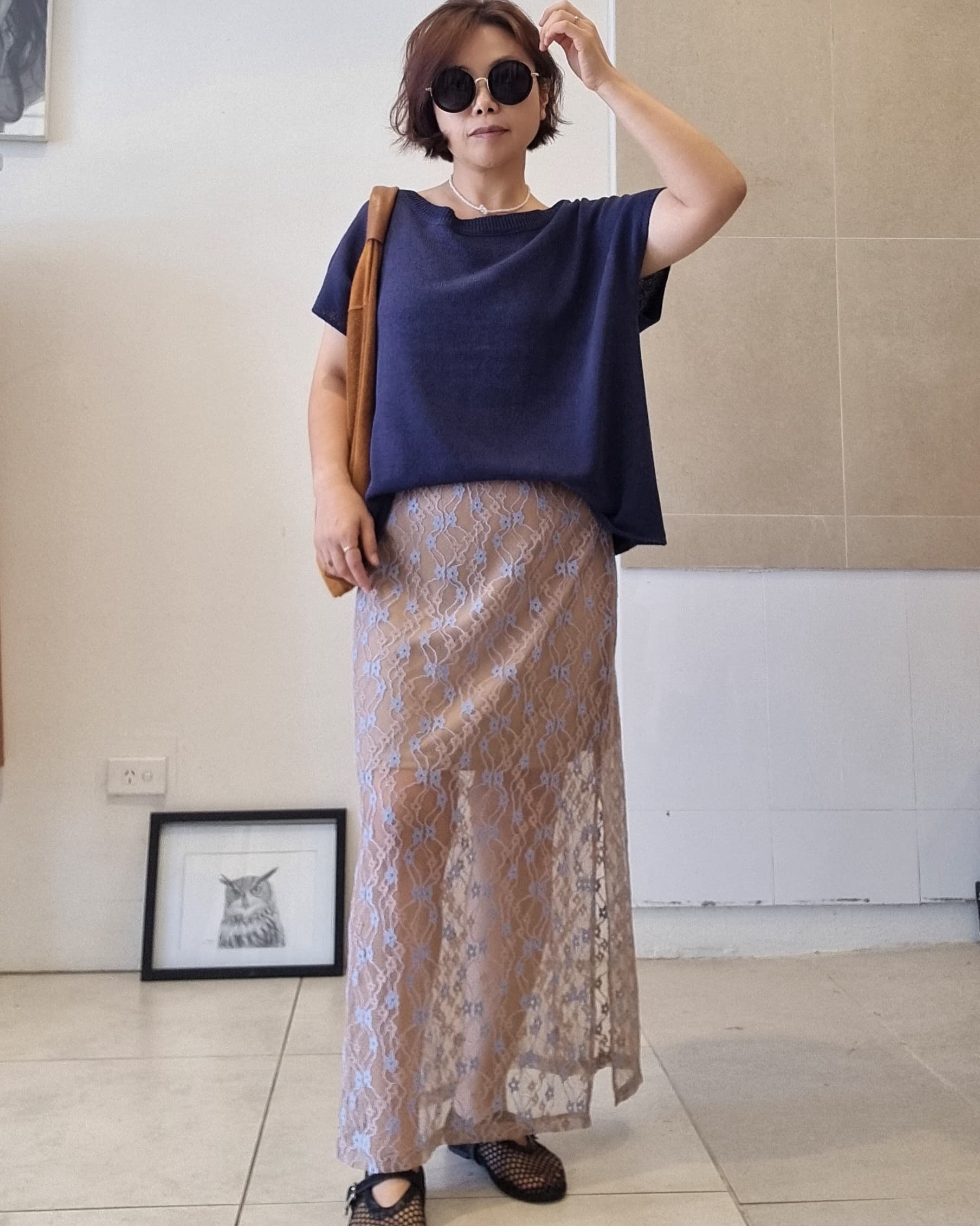 Model wearing a navy cotton relaxed-fit top styled with a beige lace maxi skirt with elastic waist and knee-length lining.