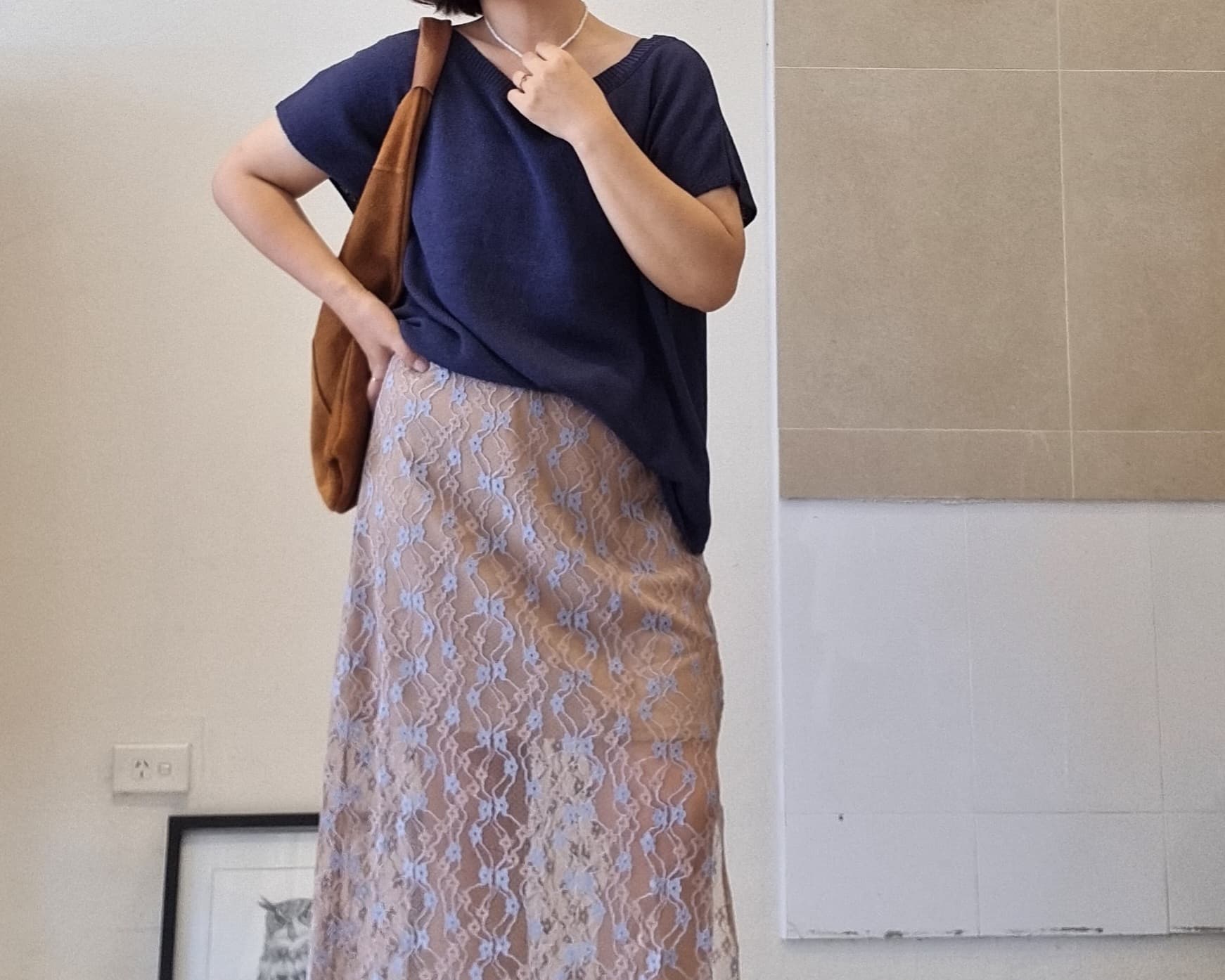 Navy cotton off-shoulder relaxed-fit top paired with a beige lace maxi skirt with elastic waist.
