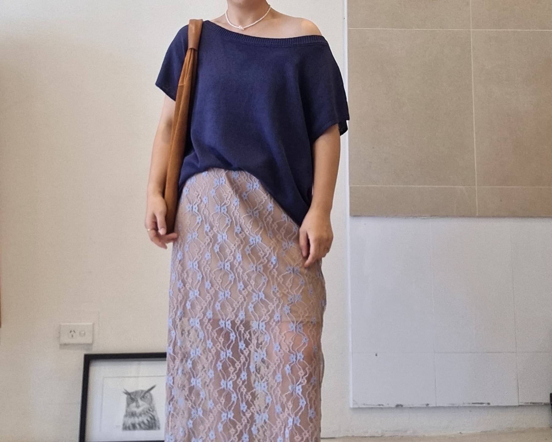 Model wearing a navy cotton off-shoulder relaxed-fit top styled with a beige lace maxi skirt.