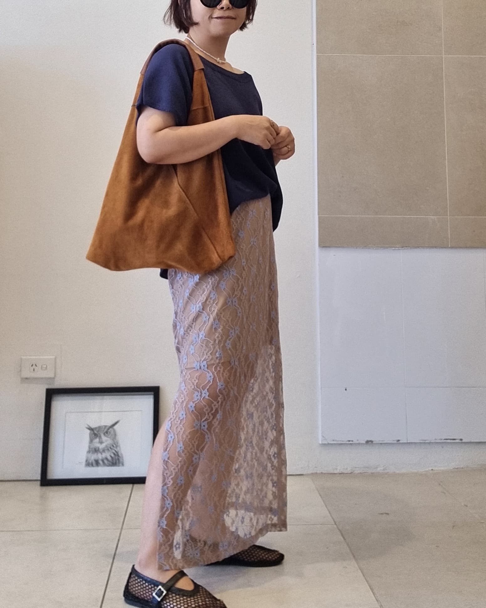 Side view of a delicate lace maxi skirt with floral pattern and elastic waist, paired with a navy top for a relaxed everyday look.