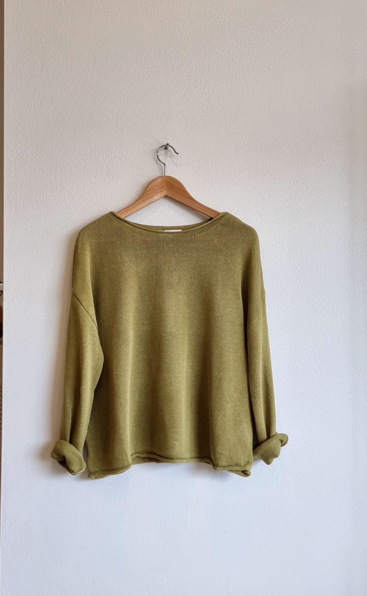 Green lightweight knit top on wooden hanger, front view
