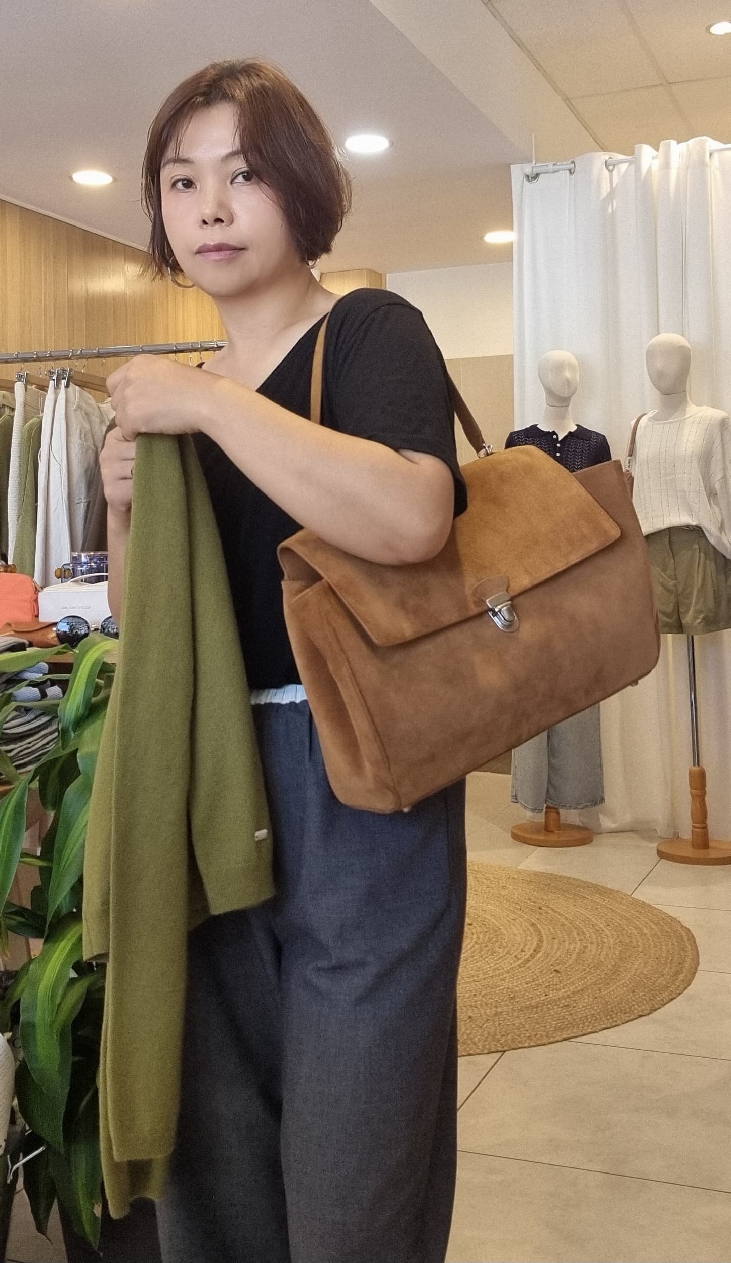 Side view of model carrying camel suede shoulder bag