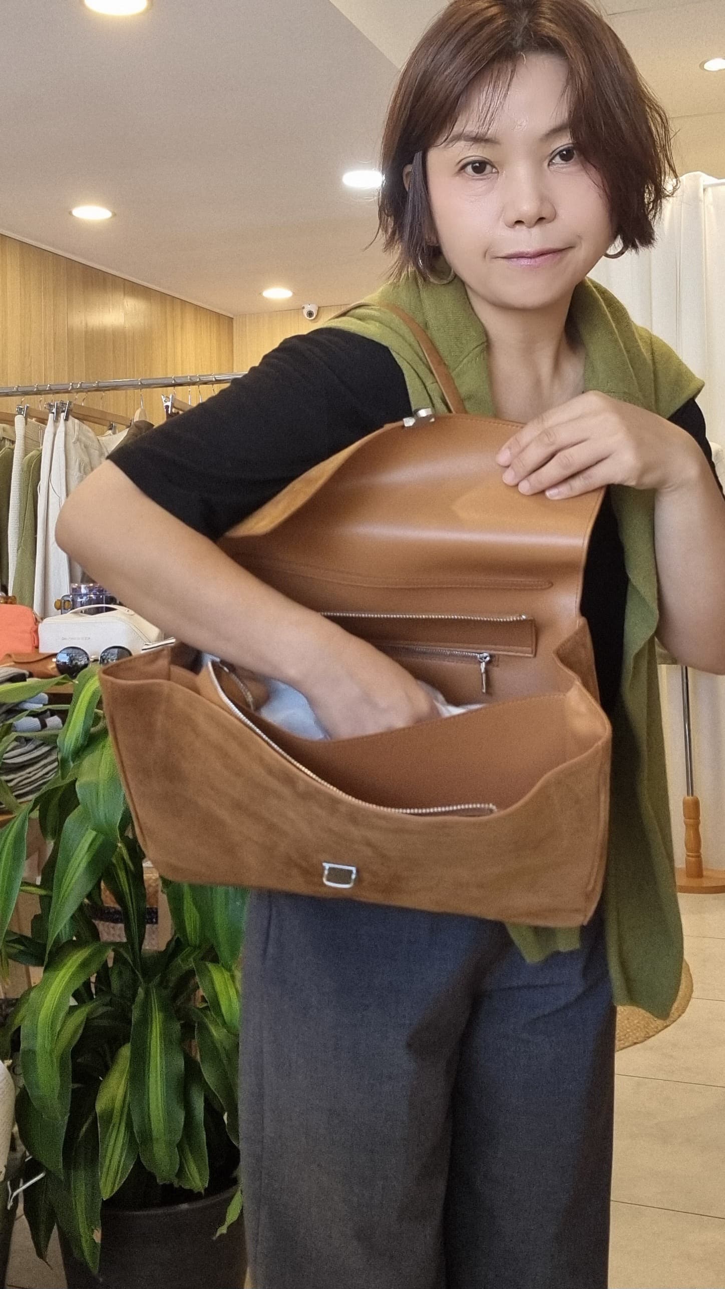 Front view of model holding camel suede leather bag