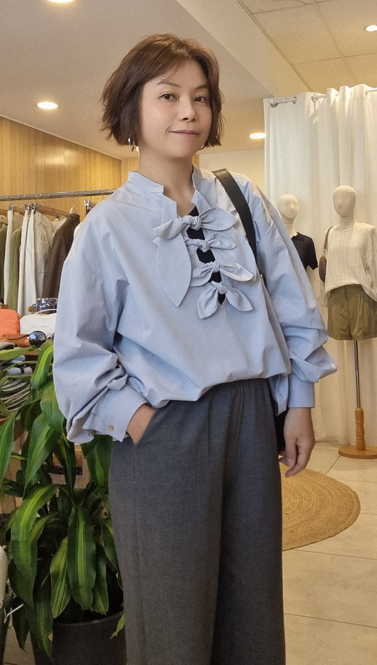 Model wearing the Cloud Blue Ribbon Top with grey trousers, front view