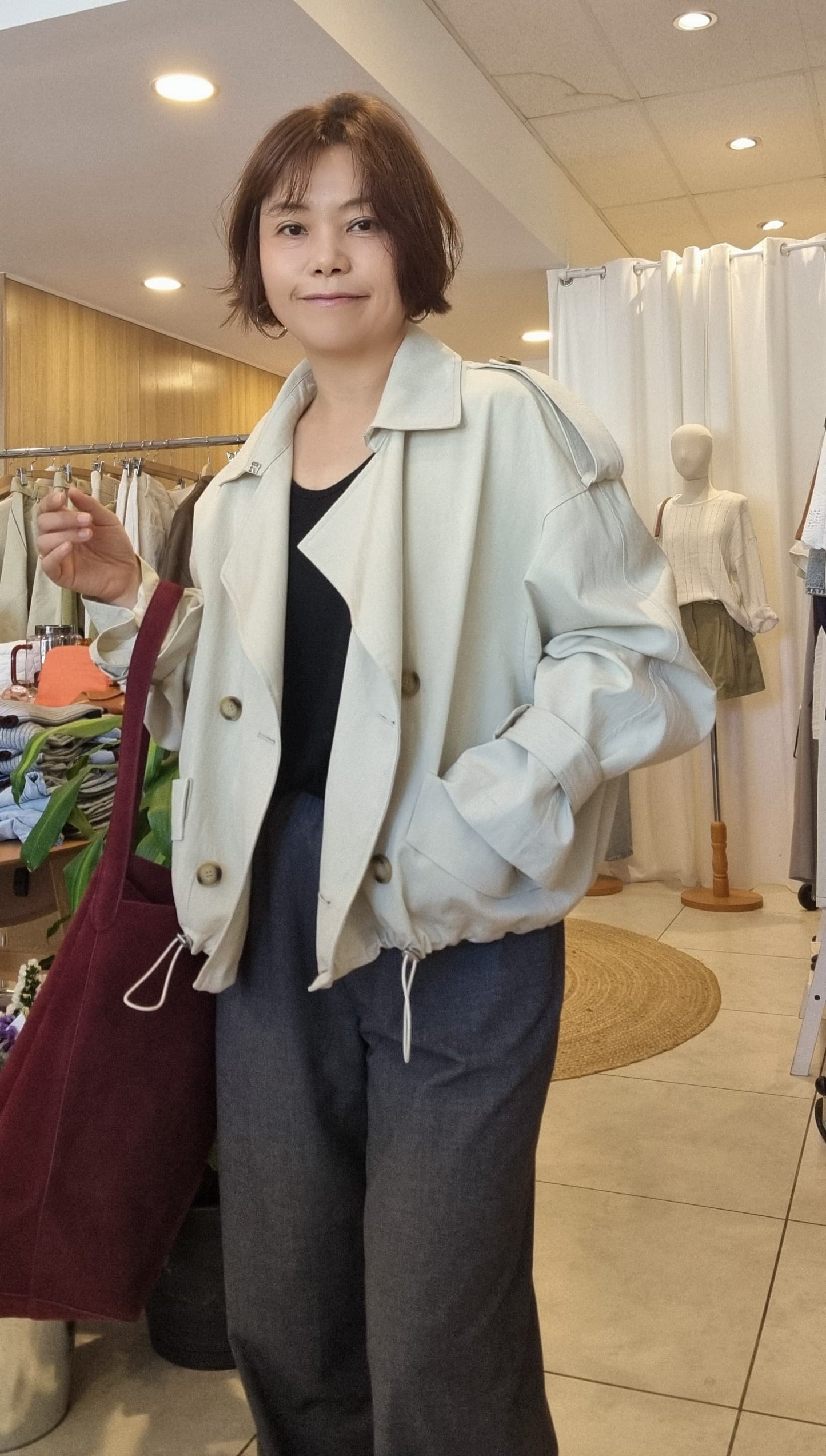 Woman wearing cream short trench coat, front look with relaxed fit