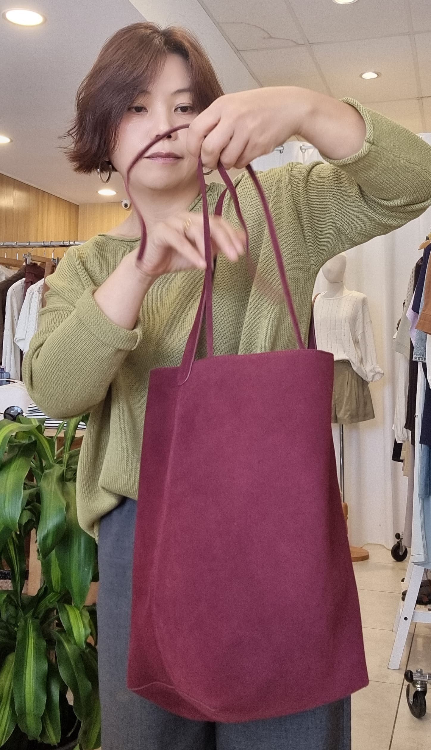 Model holding Burgundy Suede Tote, soft suede texture detail