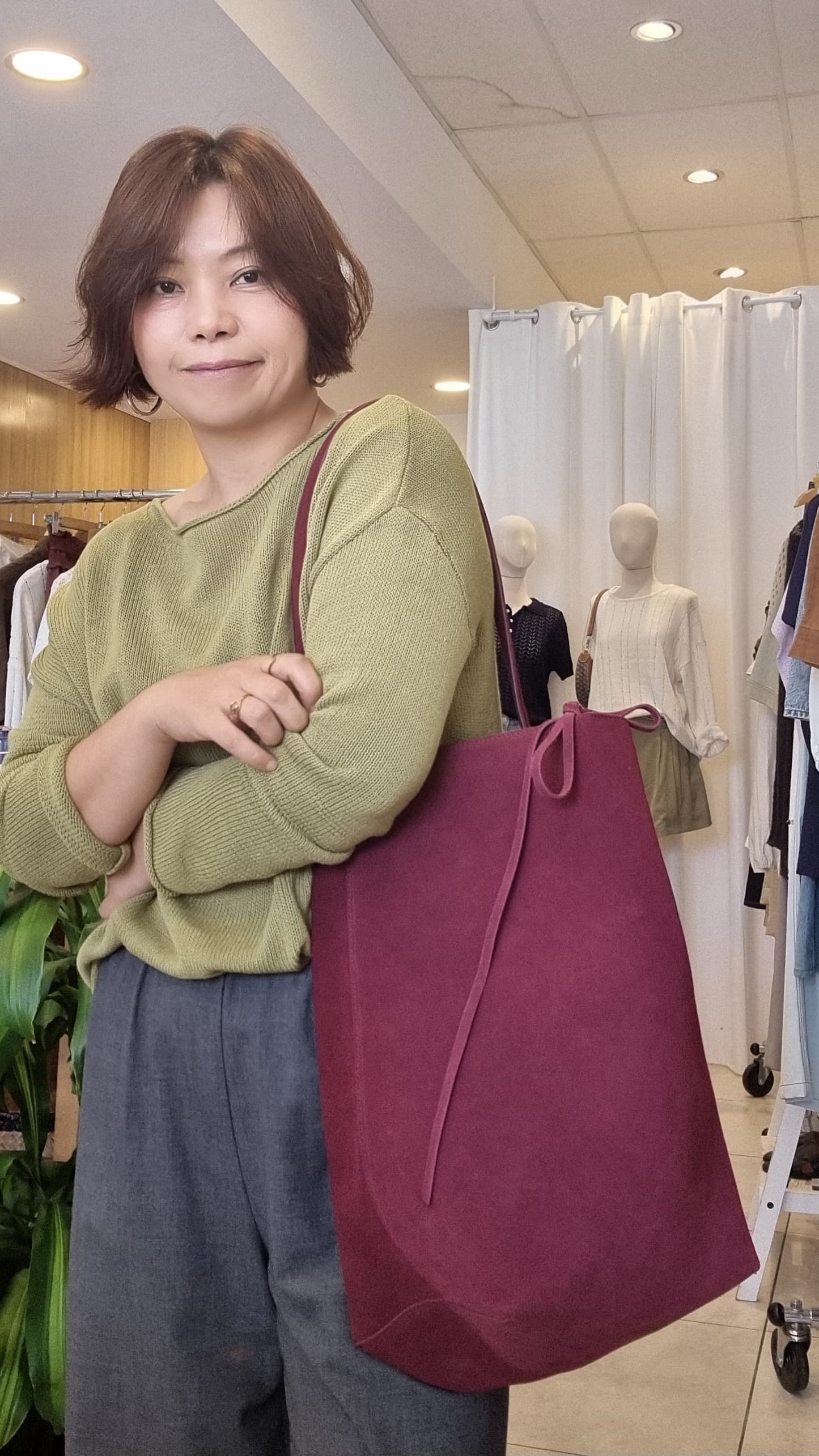 Woman styling the Burgundy Suede Tote with a green outfit, casual look