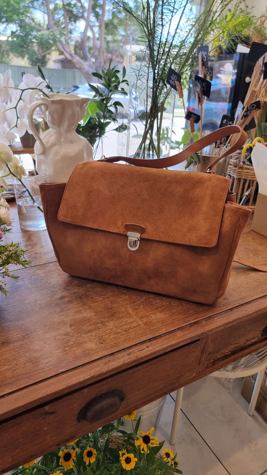 Front view of camel suede leather bag displayed on table