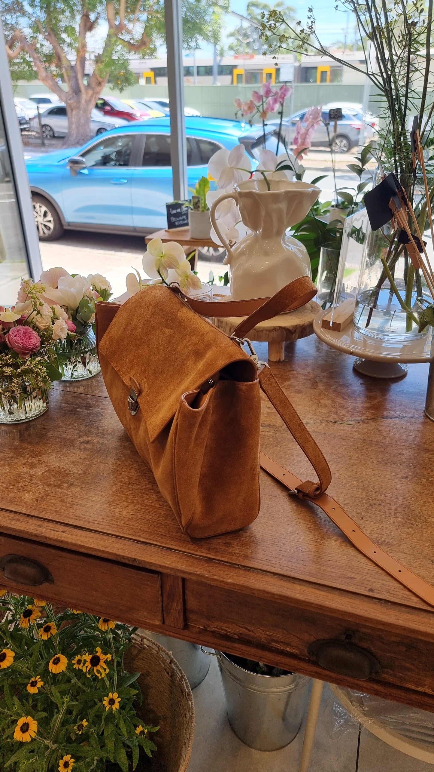 Side view of camel suede leather bag on table