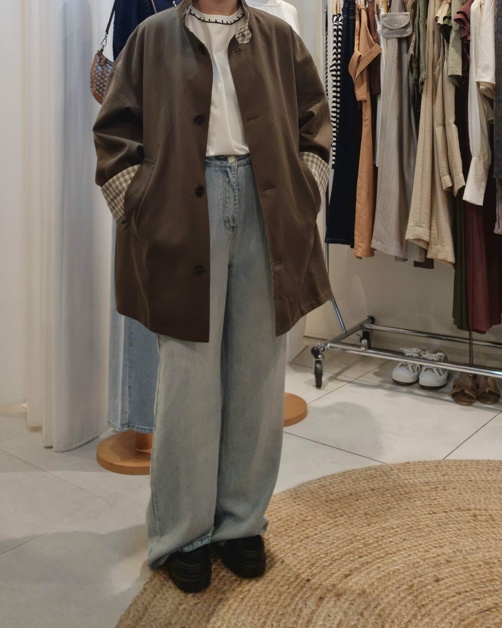 Model wearing khaki reversible trench coat with blue jeans, front view