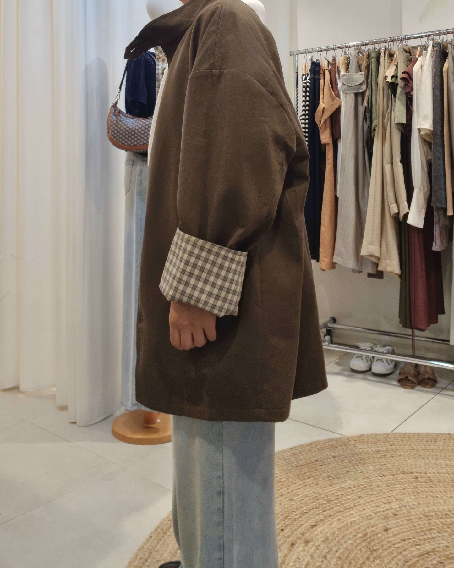 Side angle of khaki reversible trench coat styled with jeans