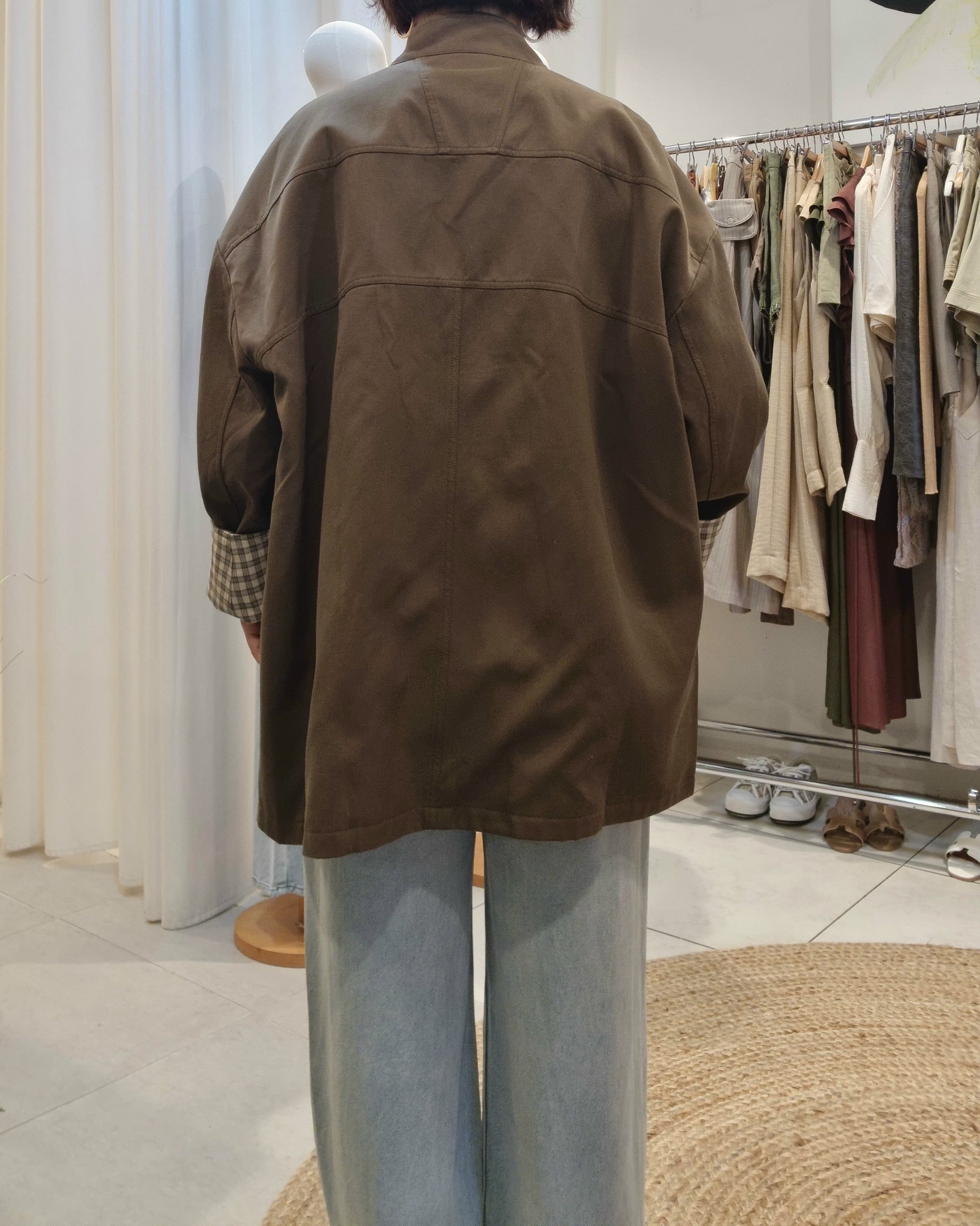 Back view of khaki oversized trench coat worn with blue jeans