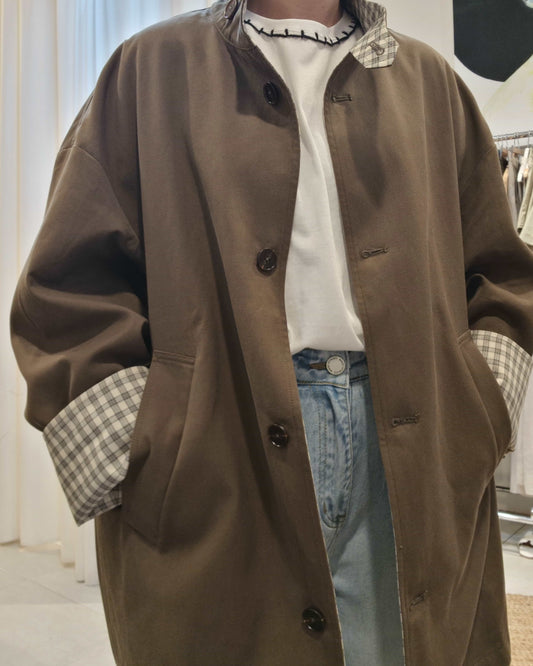 Front view of oversized khaki trench coat styled with denim jeans