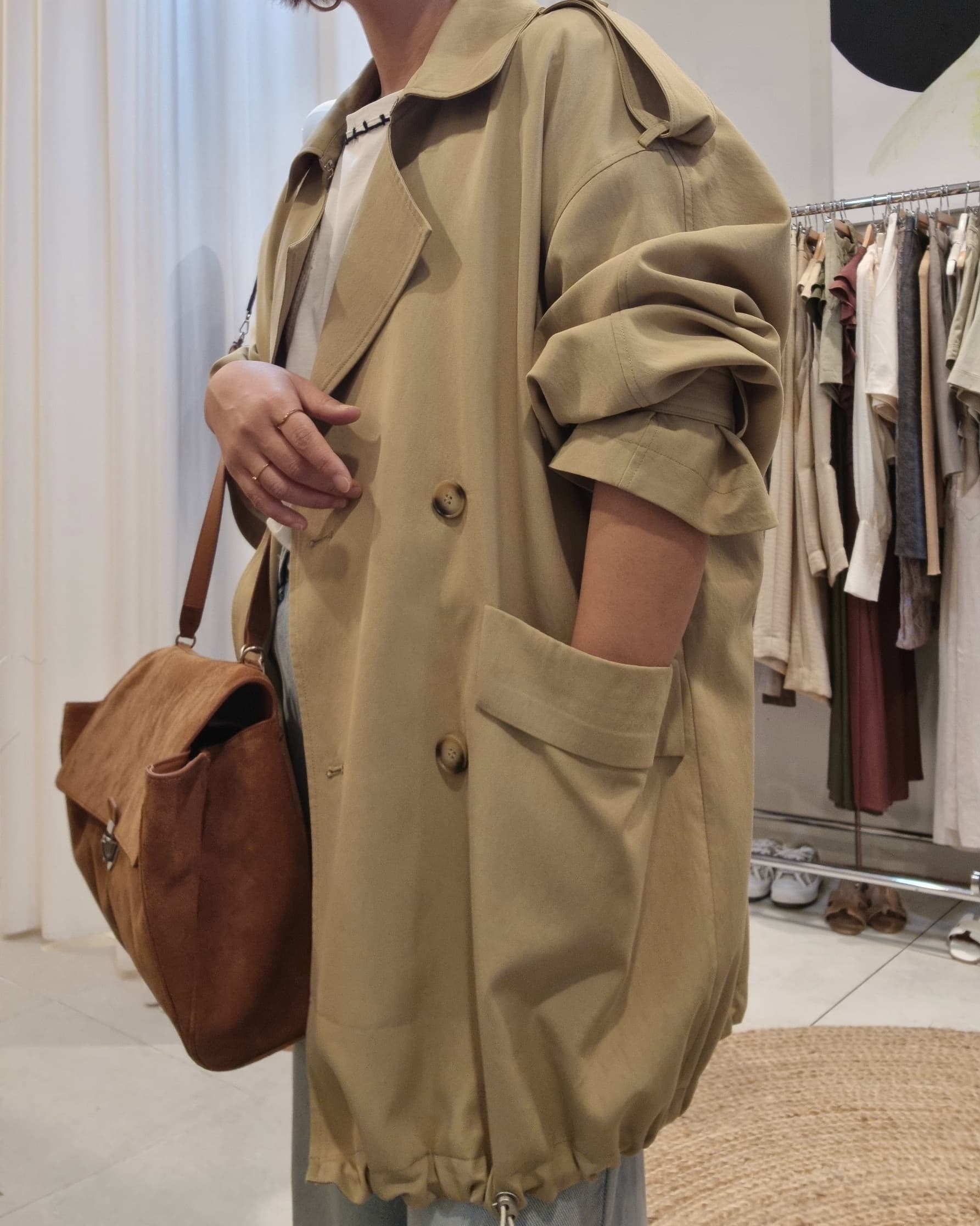 Model side view wearing Beige Luxe Trench Coat with leather brwon bag