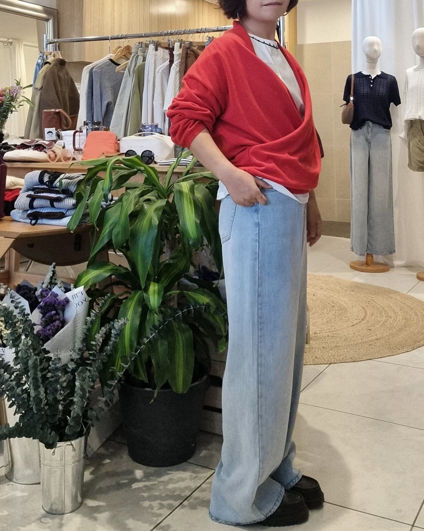 Model in red wrap knit and denim jeans, side profile showing wrap design