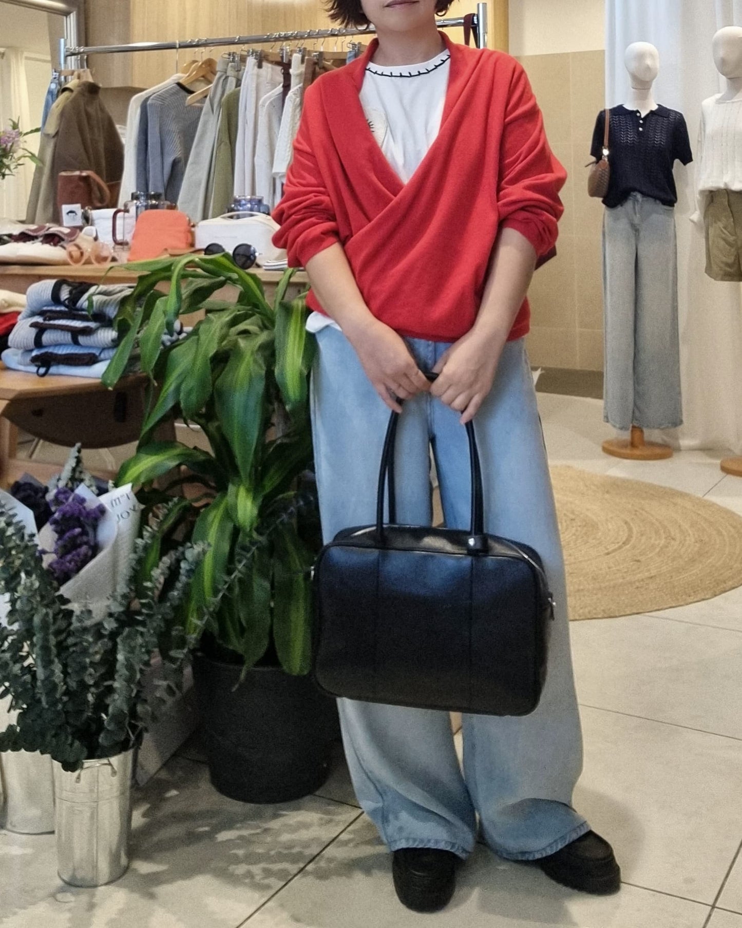 Front view of model in red wrap knit and denim jeans, relaxed everyday look