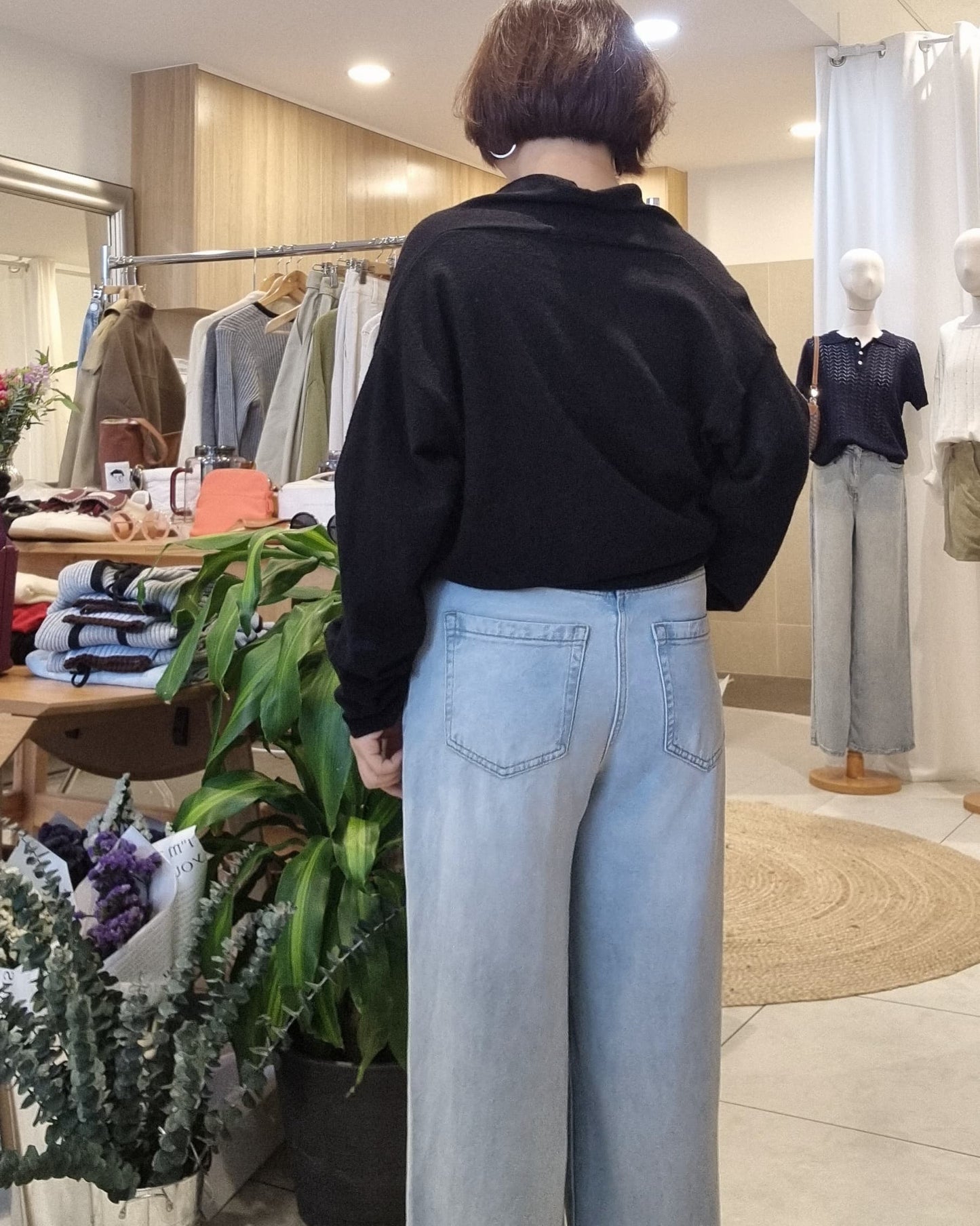 Back view of model wearing Black wrap knit with blue jeans, draped silhouette